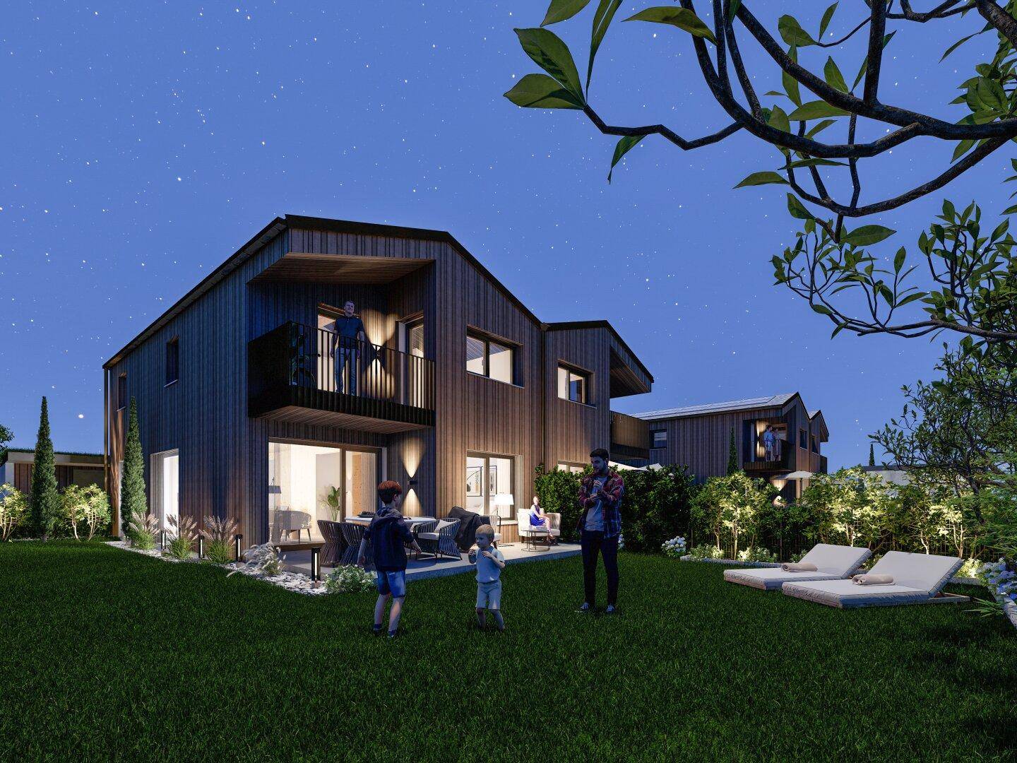 Moderne Häuser bei Nacht mit beleuchtetem Garten, Terrasse und Balkonen.