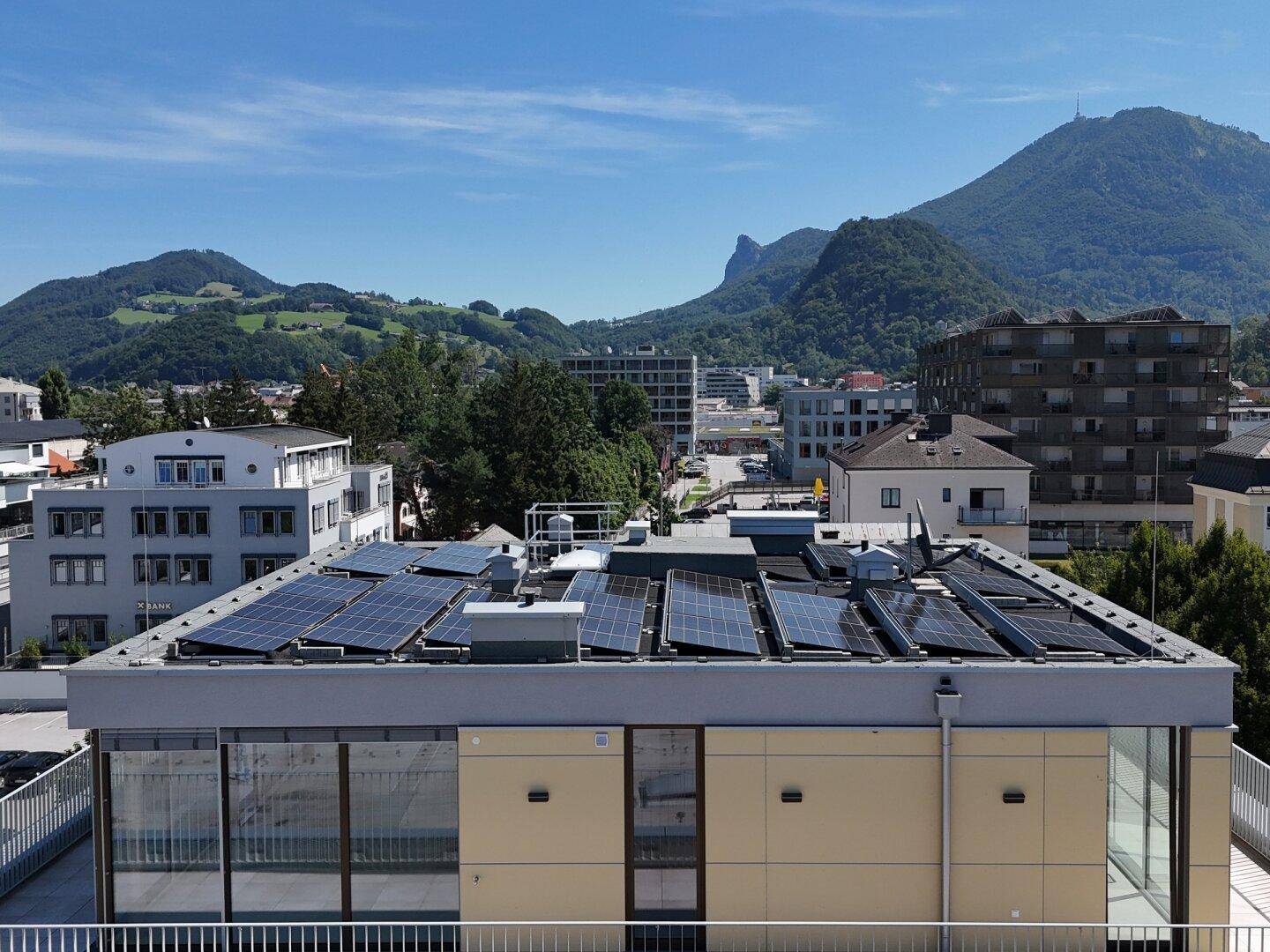 Gebäude mit Photovoltaikanlage auf dem Dach und Panoramablick auf die Berglandschaft.