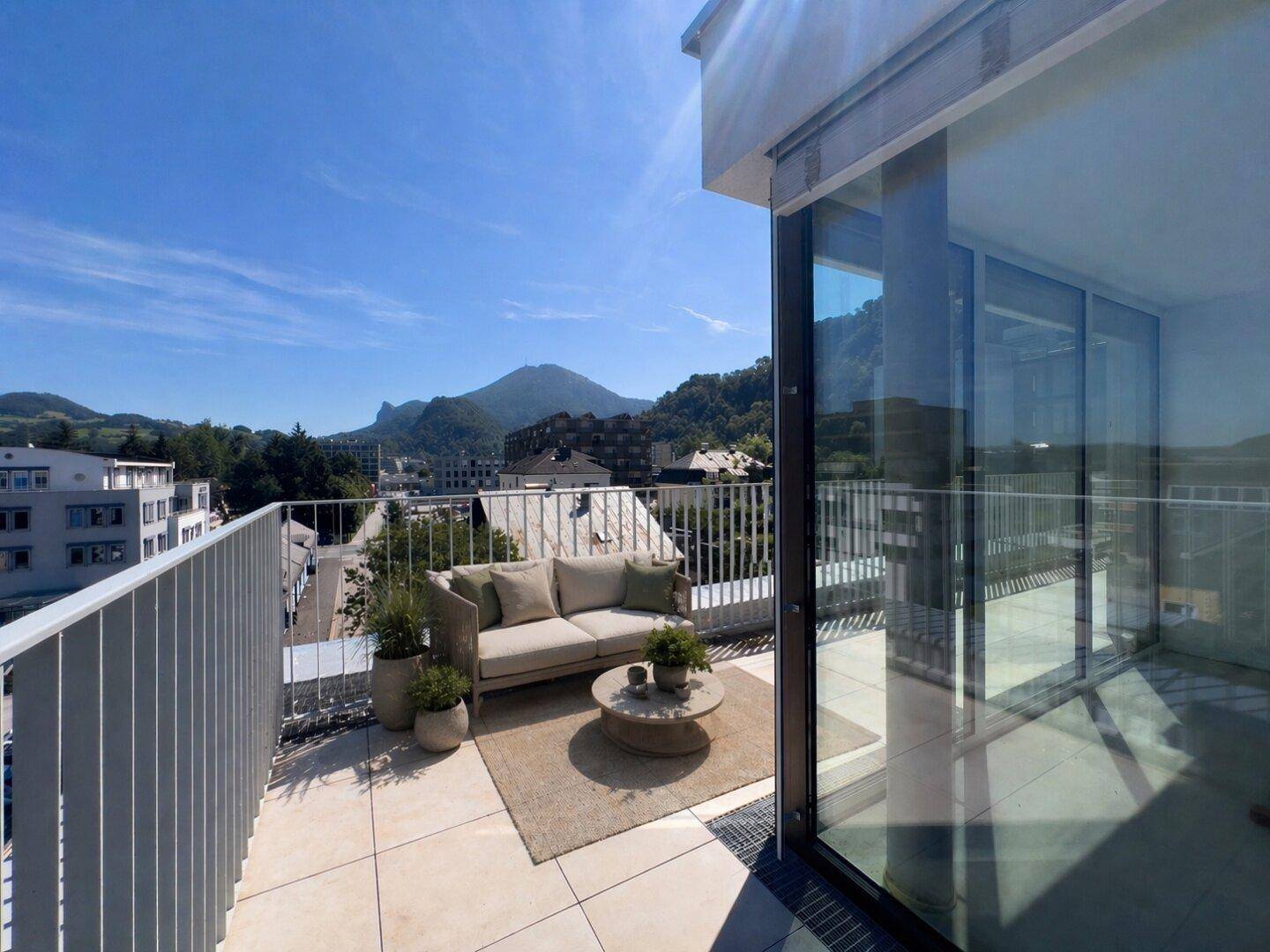 Sonniger Balkon mit bequemen Sitzmöbeln und herrlichem Blick auf die umliegende Berglandschaft.