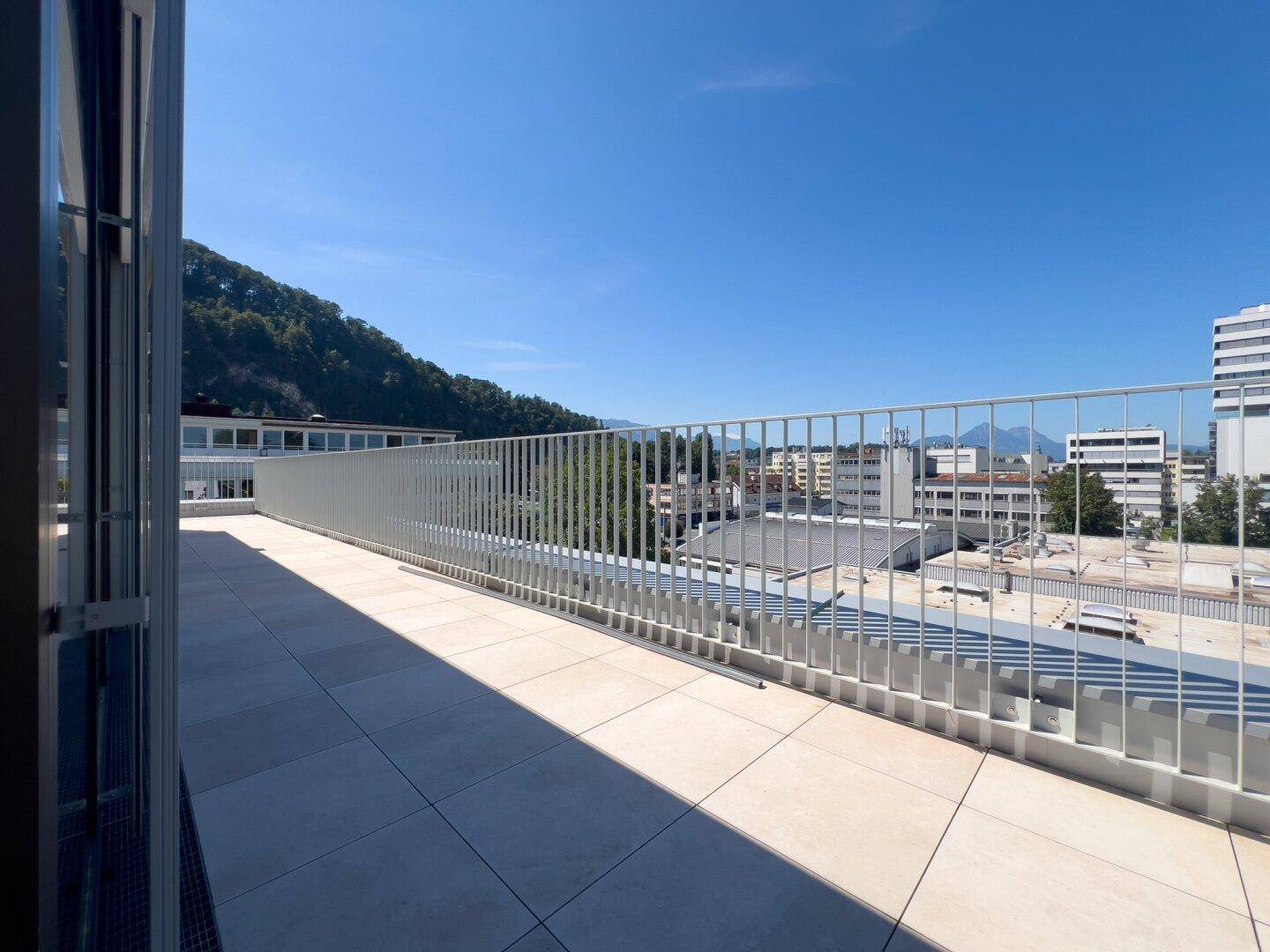 Weitläufige, unmöblierte Terrasse mit Panoramablick auf die Stadt und die umliegenden Berge.