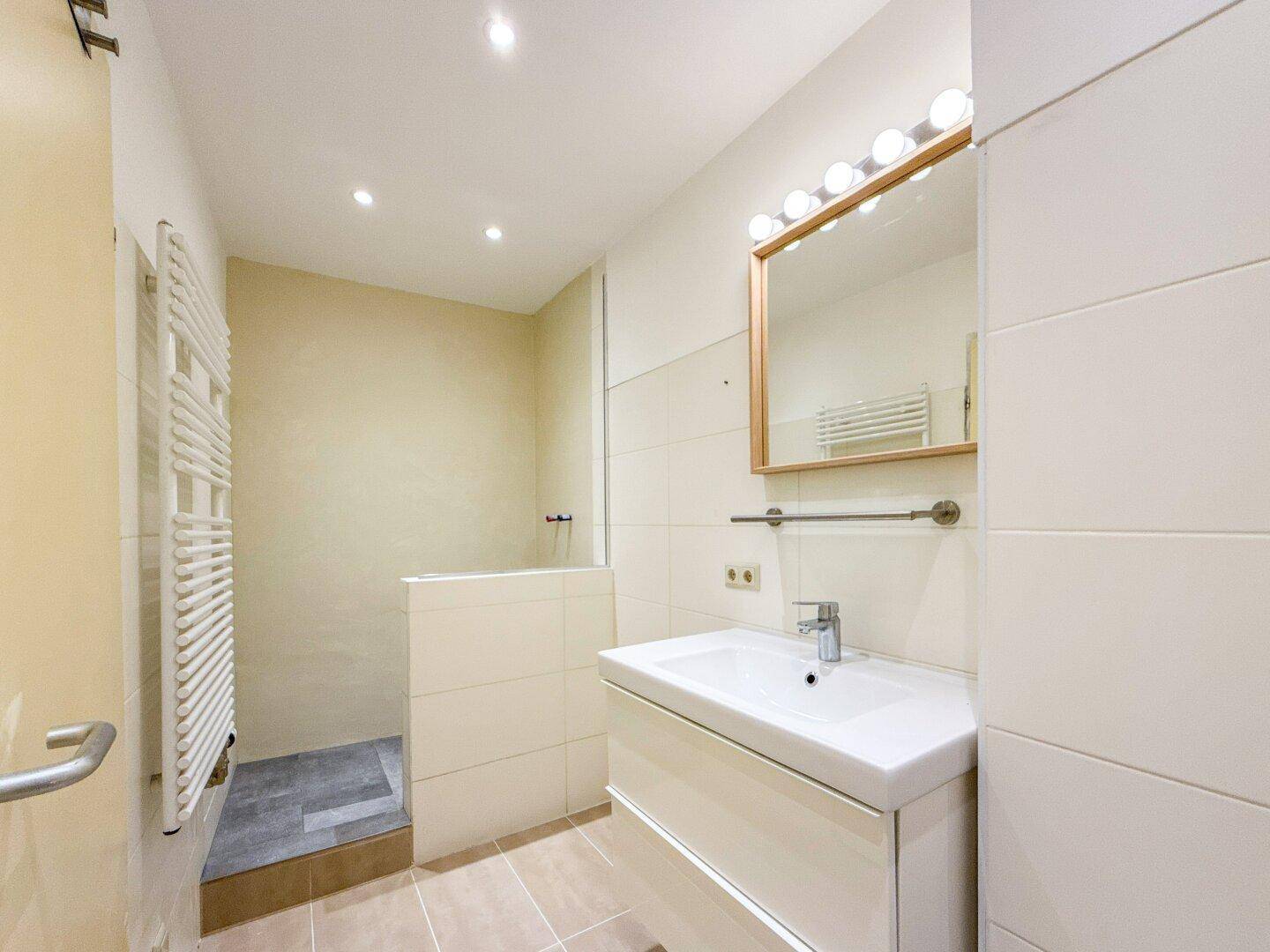Modernes Badezimmer mit begehbarer Dusche, Einzelwaschbecken und beheiztem Handtuchhalter.