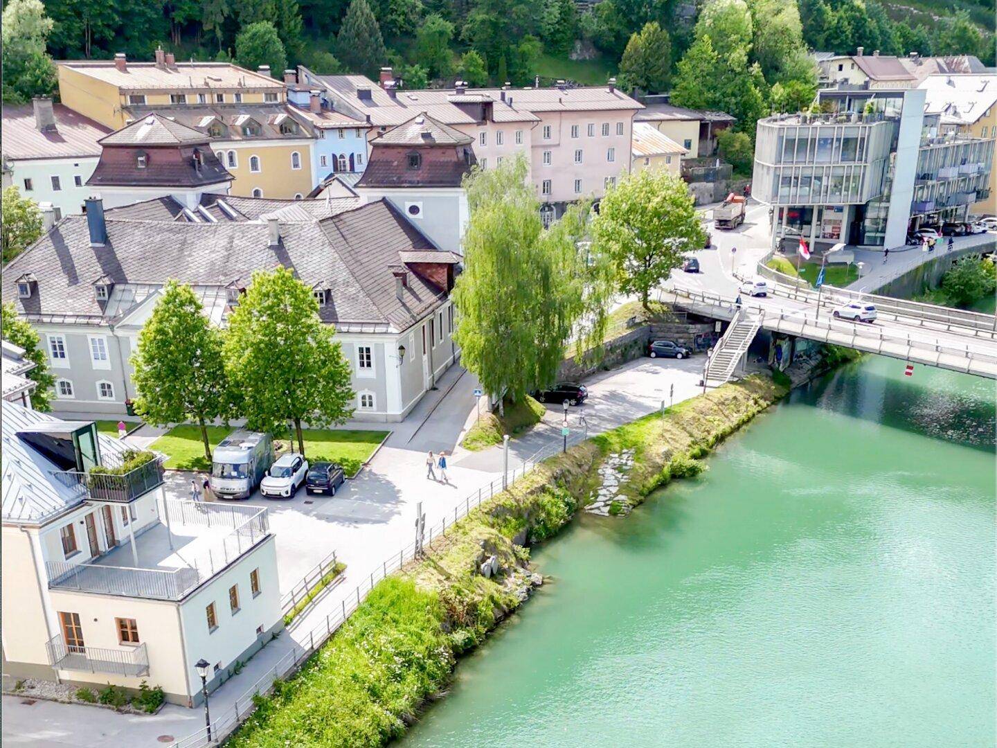 Malerische Stadtansicht mit Fluss, Brücke und historischen Gebäuden unter blauem Himmel.
