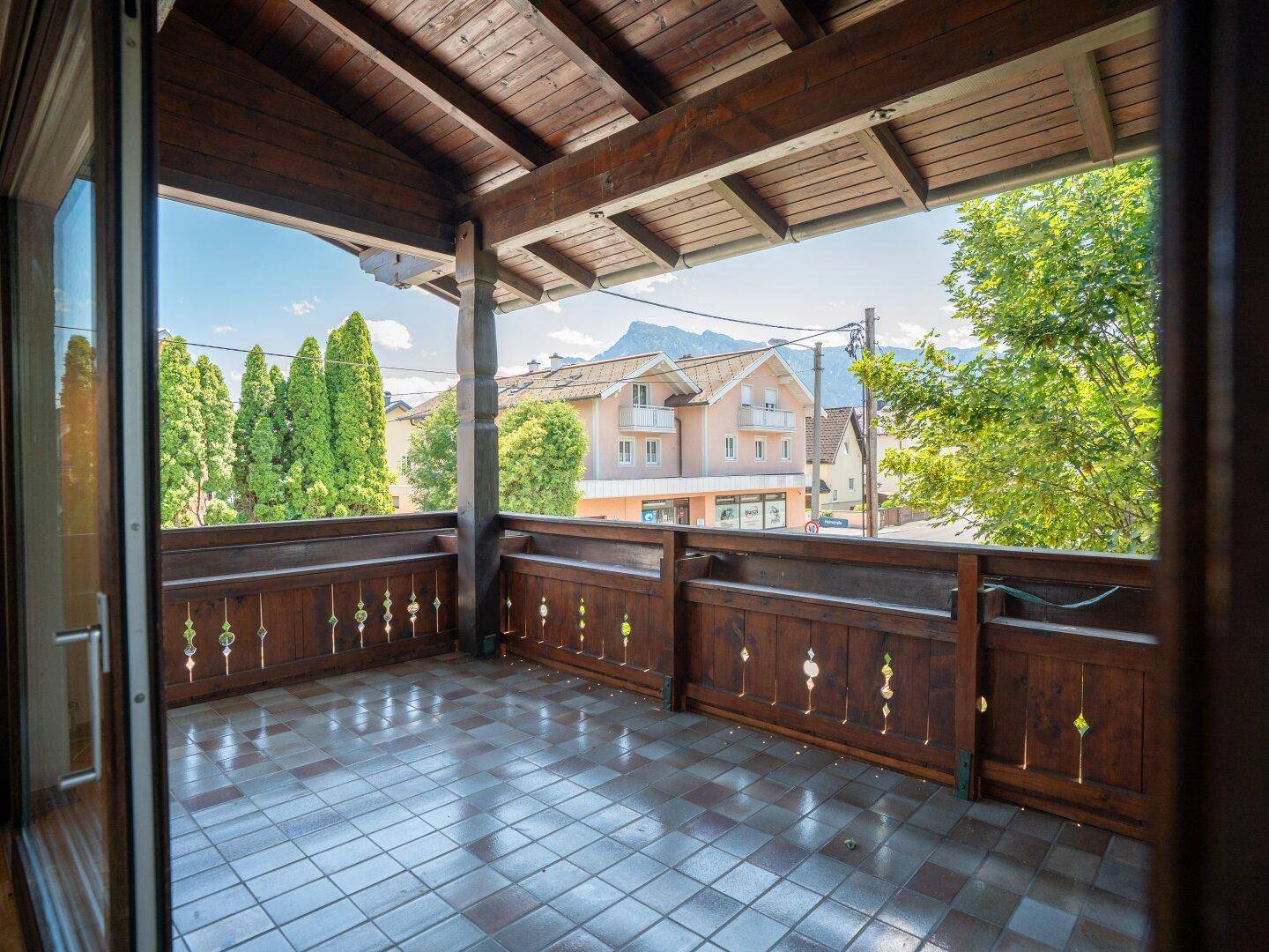 Geräumiger überdachter Balkon mit Fliesenboden und Holzbalken, bietet Bergblick in die Ferne.