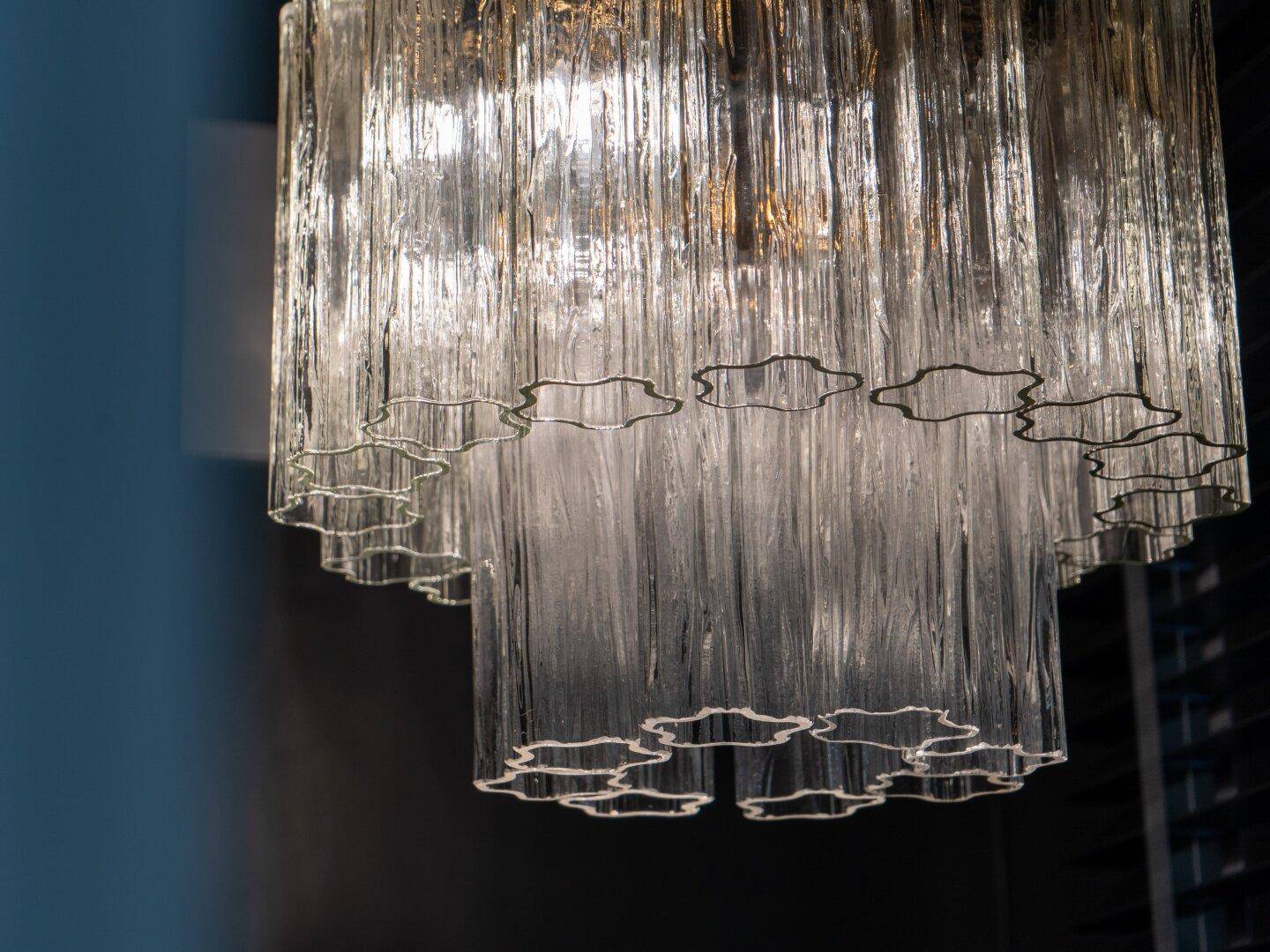 Nahaufnahme eines eleganten Kronleuchters aus Glasröhren, der ein diffuses Licht spendet.