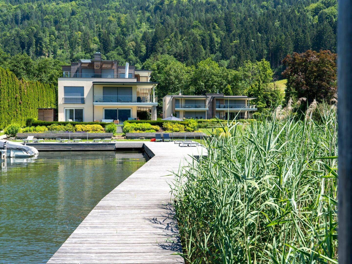 Moderne Wohngebäude am Seeufer mit Balkonen und direktem Zugang zum Wassersteg.