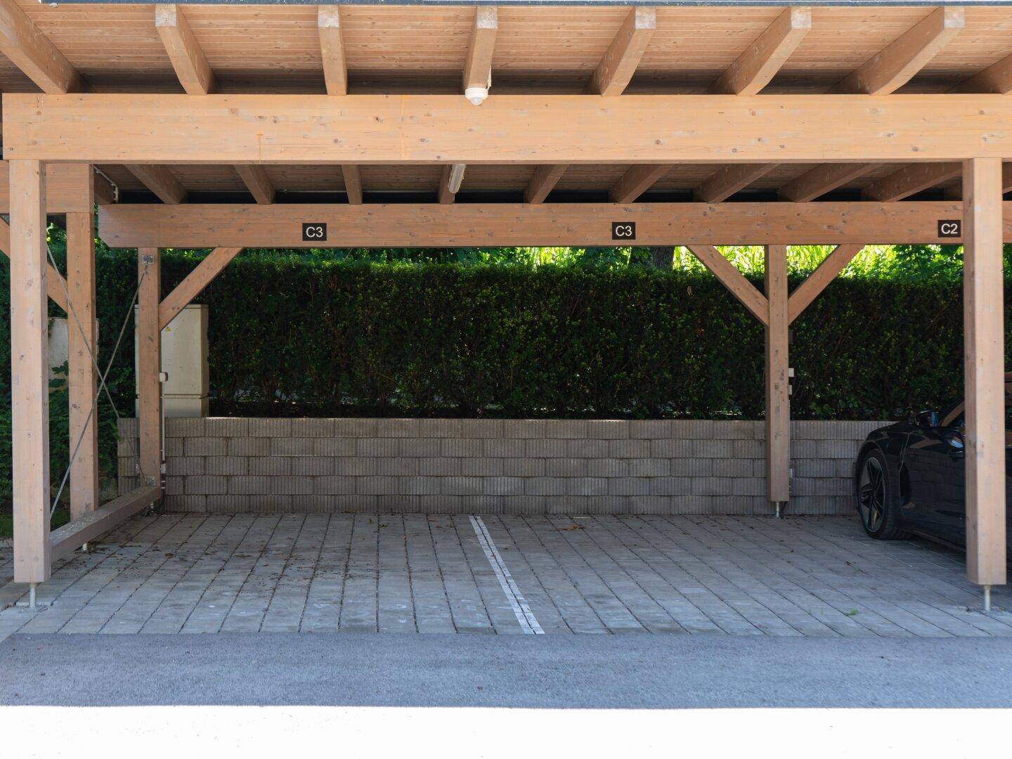 Überdachter Holz-Carport mit mehreren Stellplätzen, bietet Schutz für Fahrzeuge.