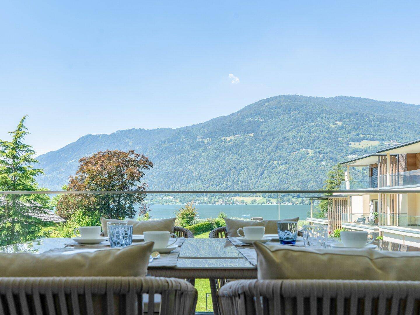 Essbereich auf der Terrasse mit gedecktem Tisch, genießt eine herrliche Aussicht auf den See und die Berge.