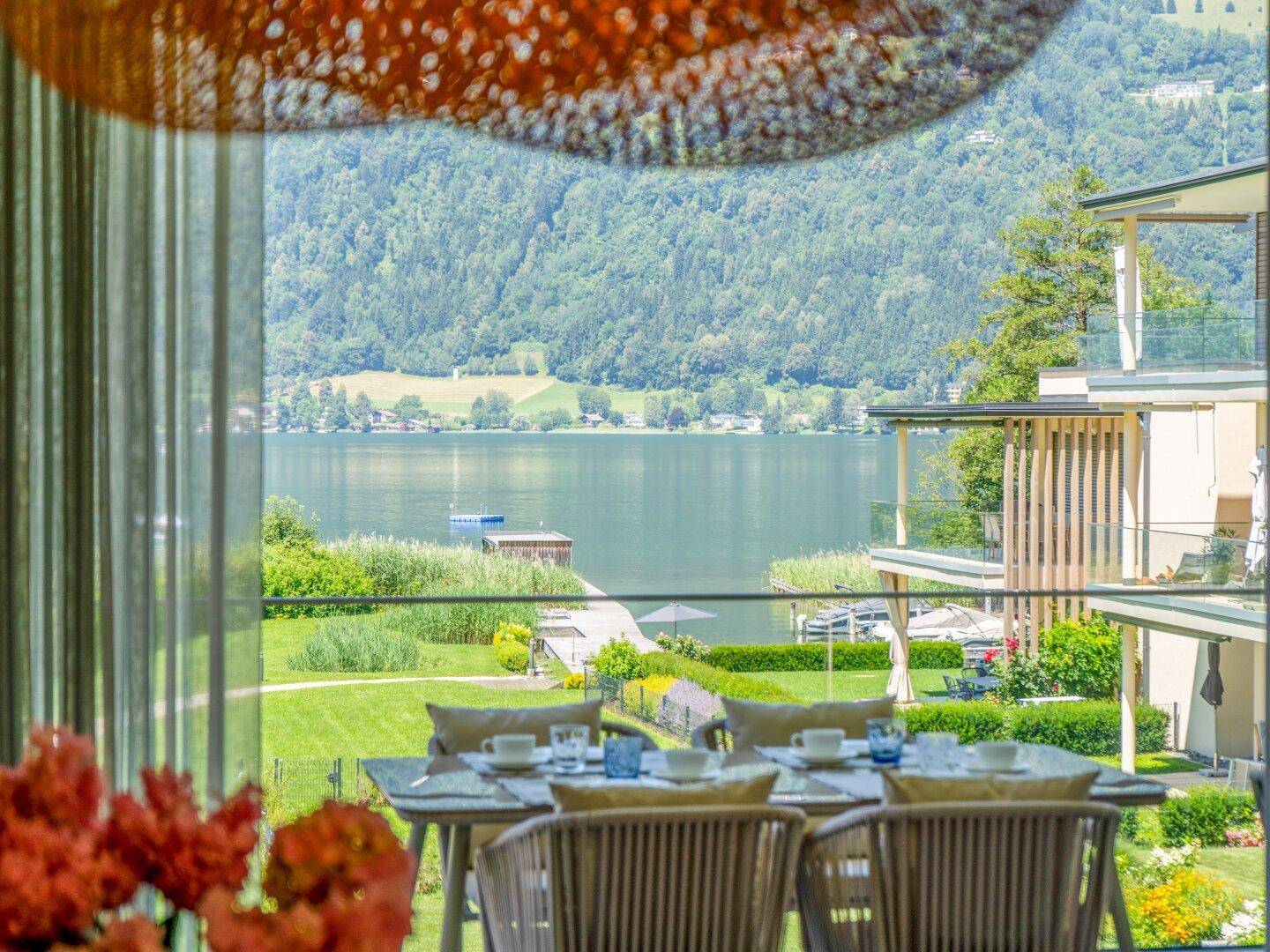Gemütlicher Essbereich auf der Terrasse mit Blick auf den See, umgeben von üppiger grüner Landschaft.