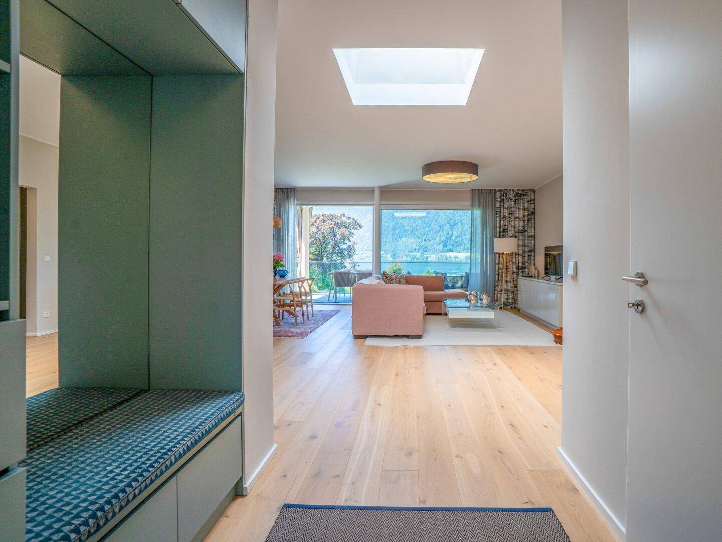 Heller Flur mit Einbauschrank und Sitzbank, führt in den offenen Wohnbereich mit Seeblick.