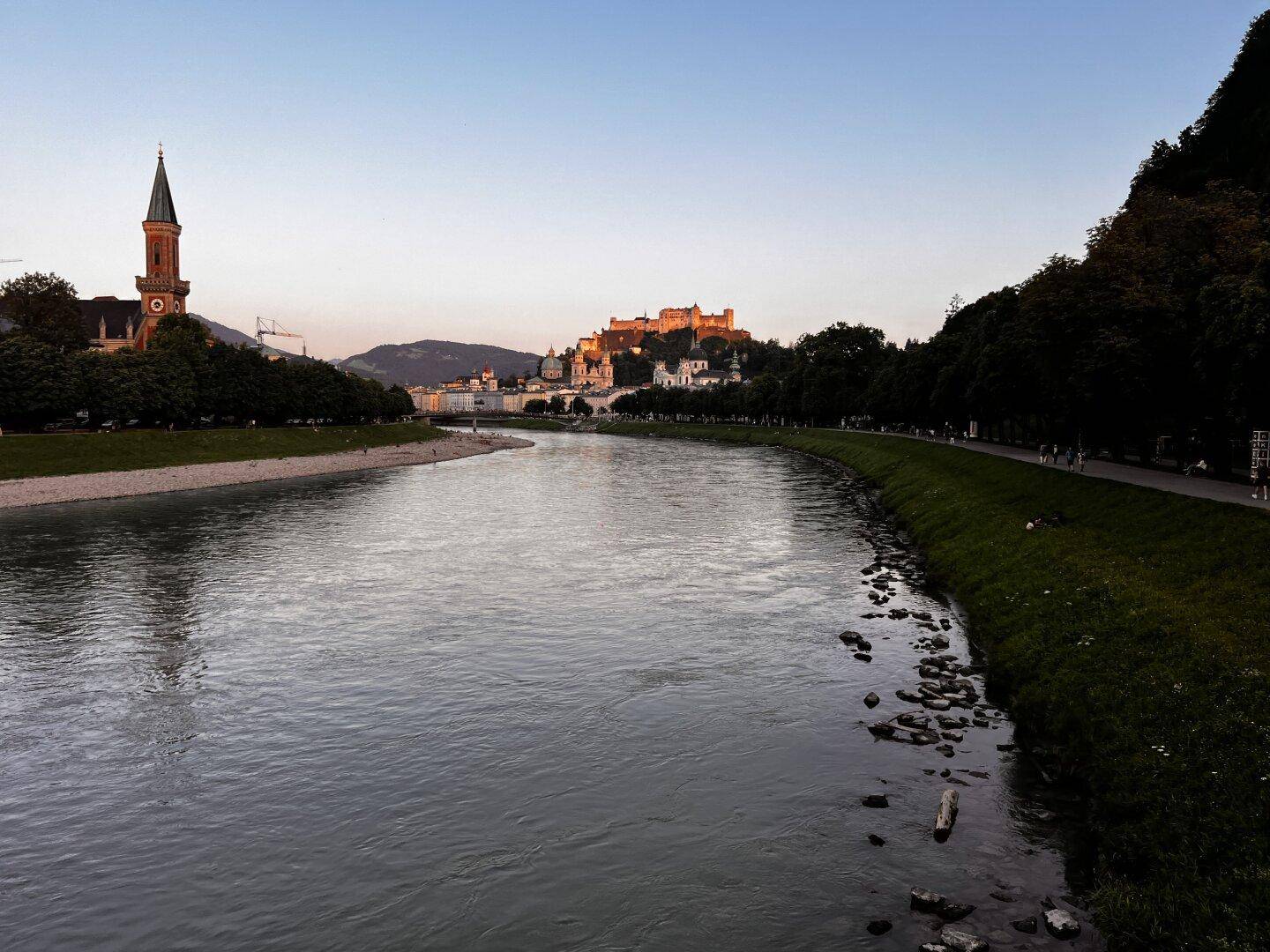 Weitläufiger Flussblick mit Stadtpanorama und der Festung Hohensalzburg im Hintergrund.