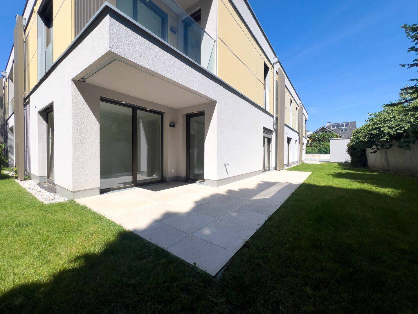 Großzügige Terrasse mit angrenzendem Rasenbereich und Zugang zu den Wohnräumen.
