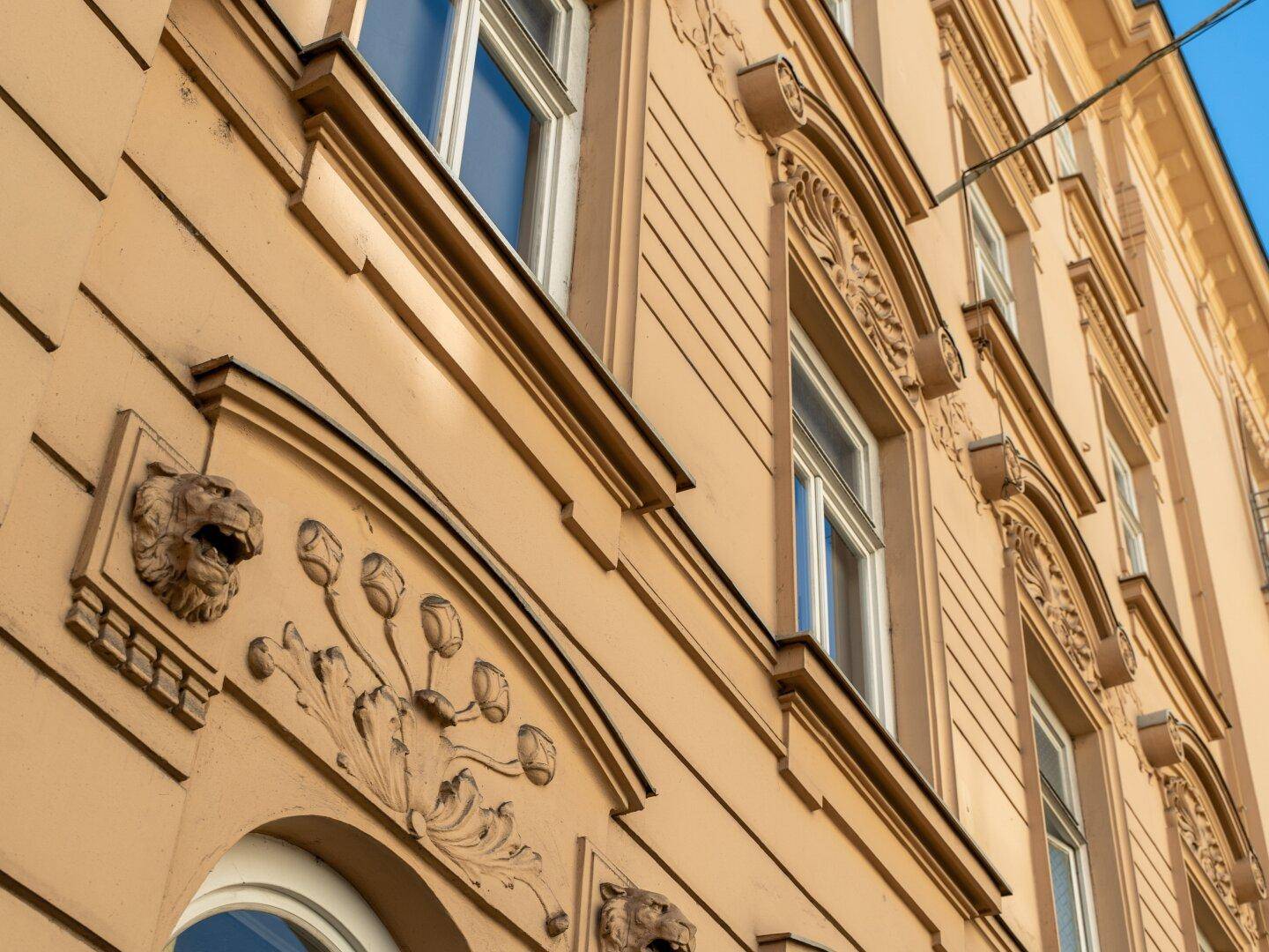 Detailaufnahme einer historischen Fassade mit kunstvollen Verzierungen und Fenstern.