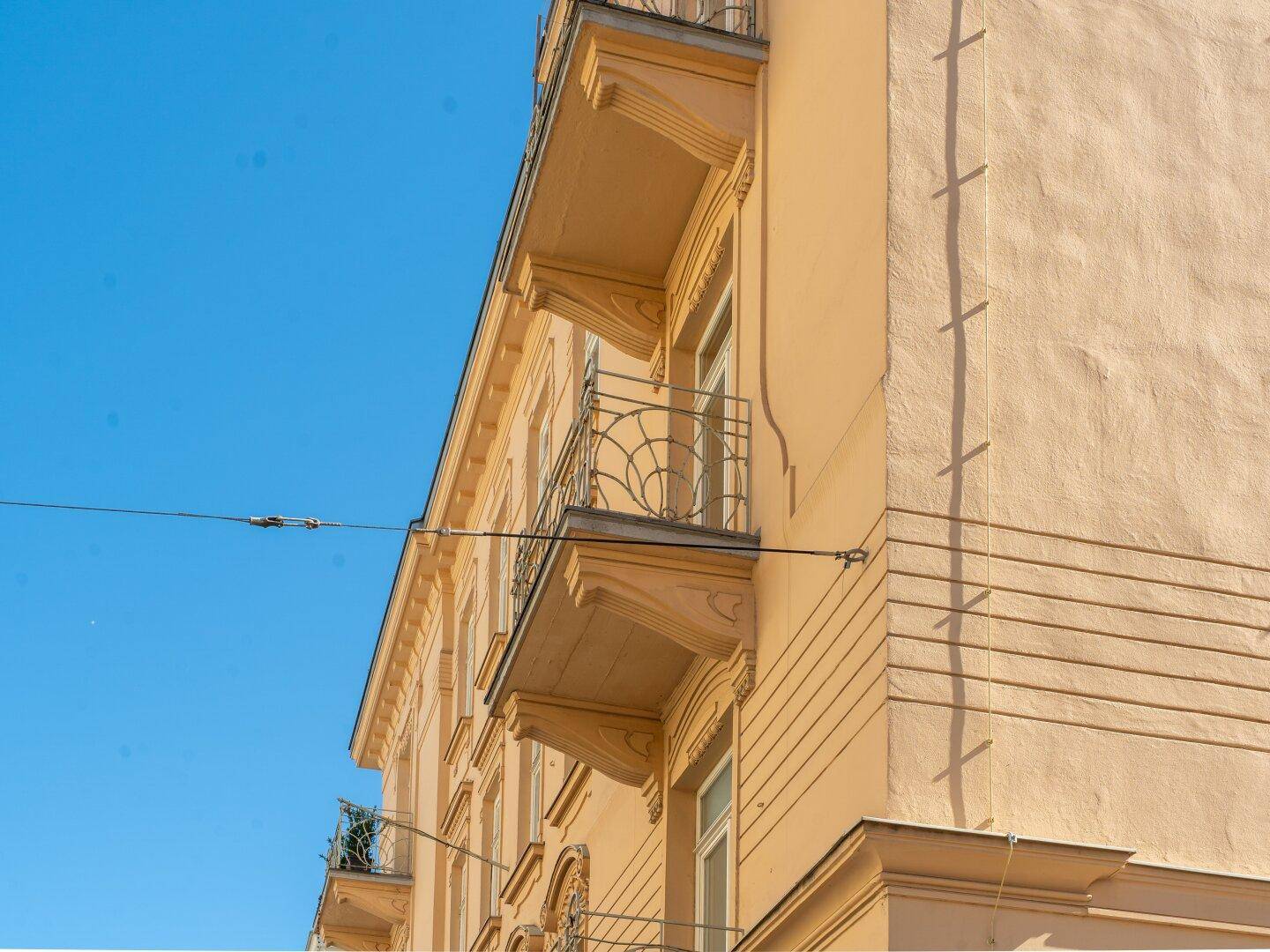 Historische Fassade eines Gebäudes mit mehreren Balkonen und dekorativen Elementen.