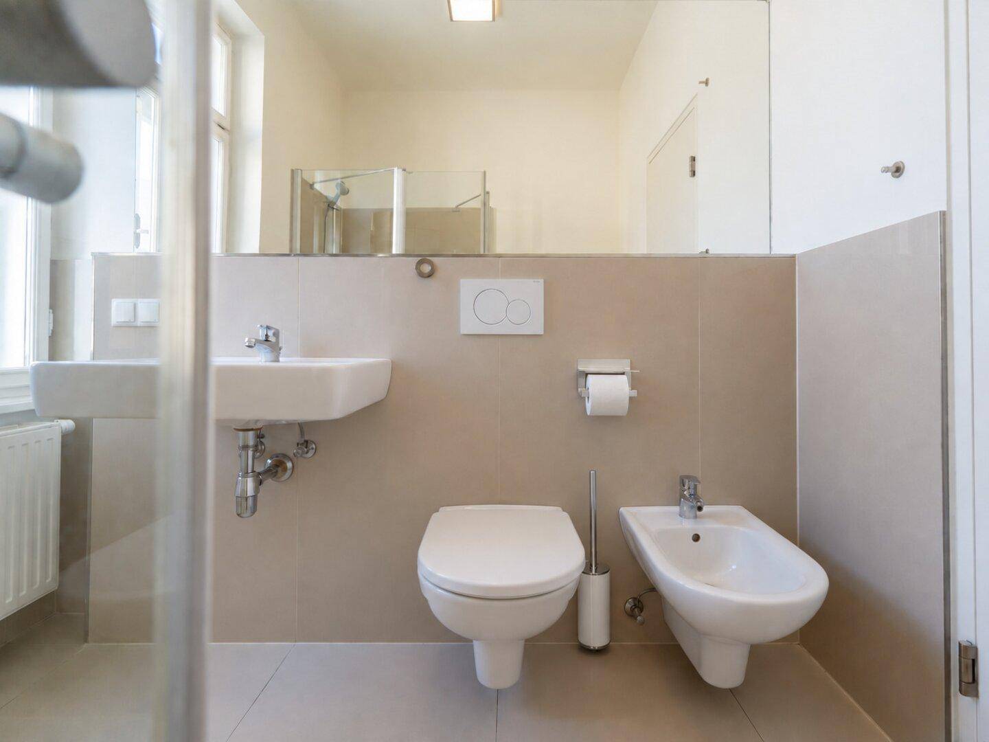 Modernes Badezimmer mit WC, Bidet, Einzelwaschbecken und großem Spiegel.