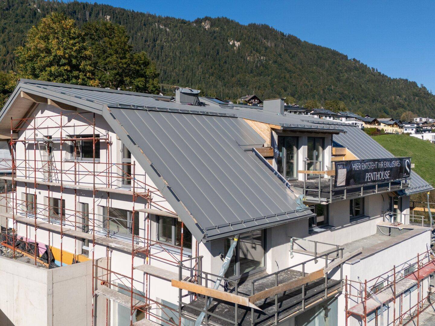 Neubau eines Gebäudes mit modernem Dach und Gerüst, in alpiner Umgebung.