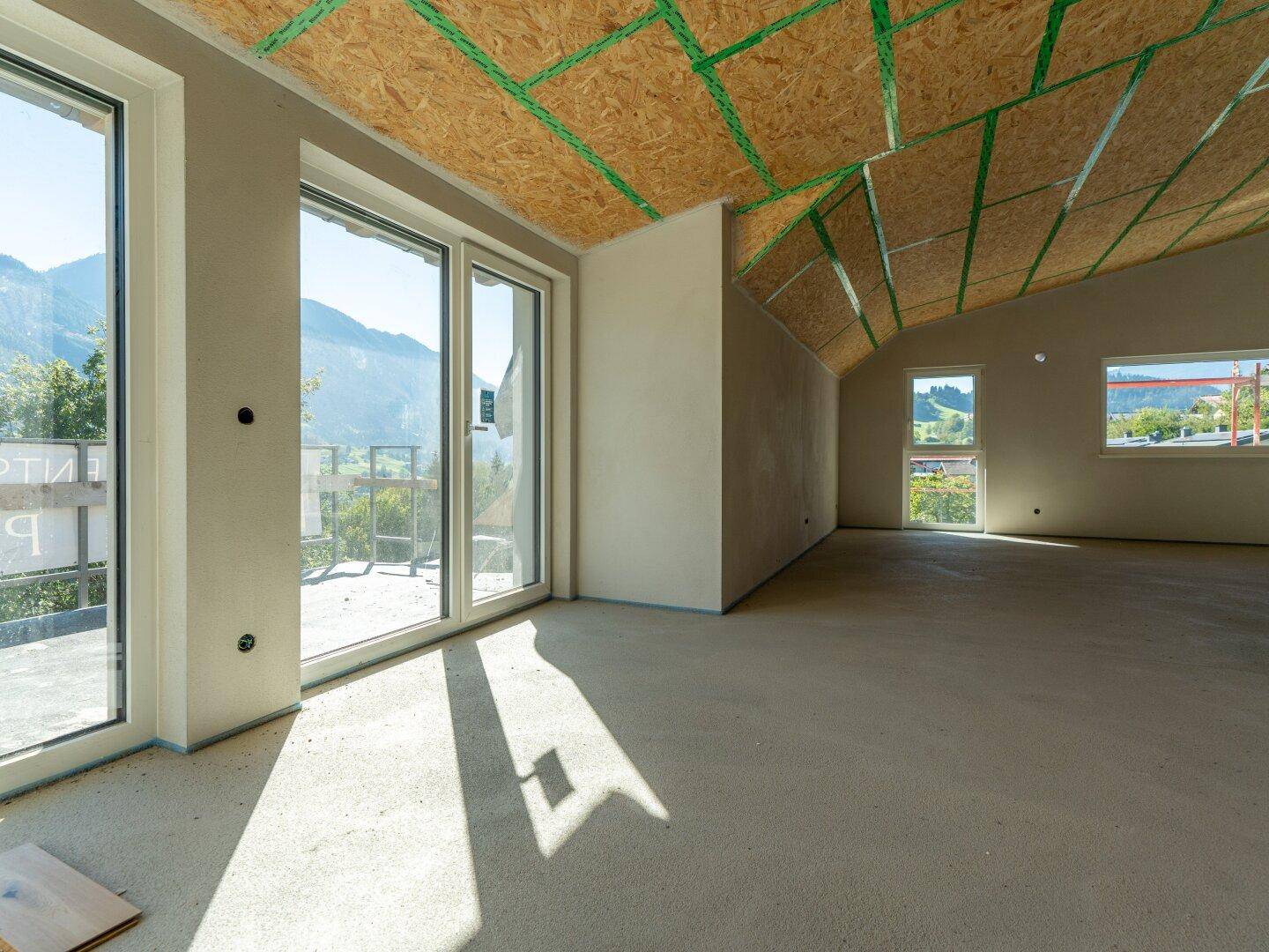 Heller Rohbau mit großen Fenstern, die einen weiten Blick auf die Berglandschaft bieten.