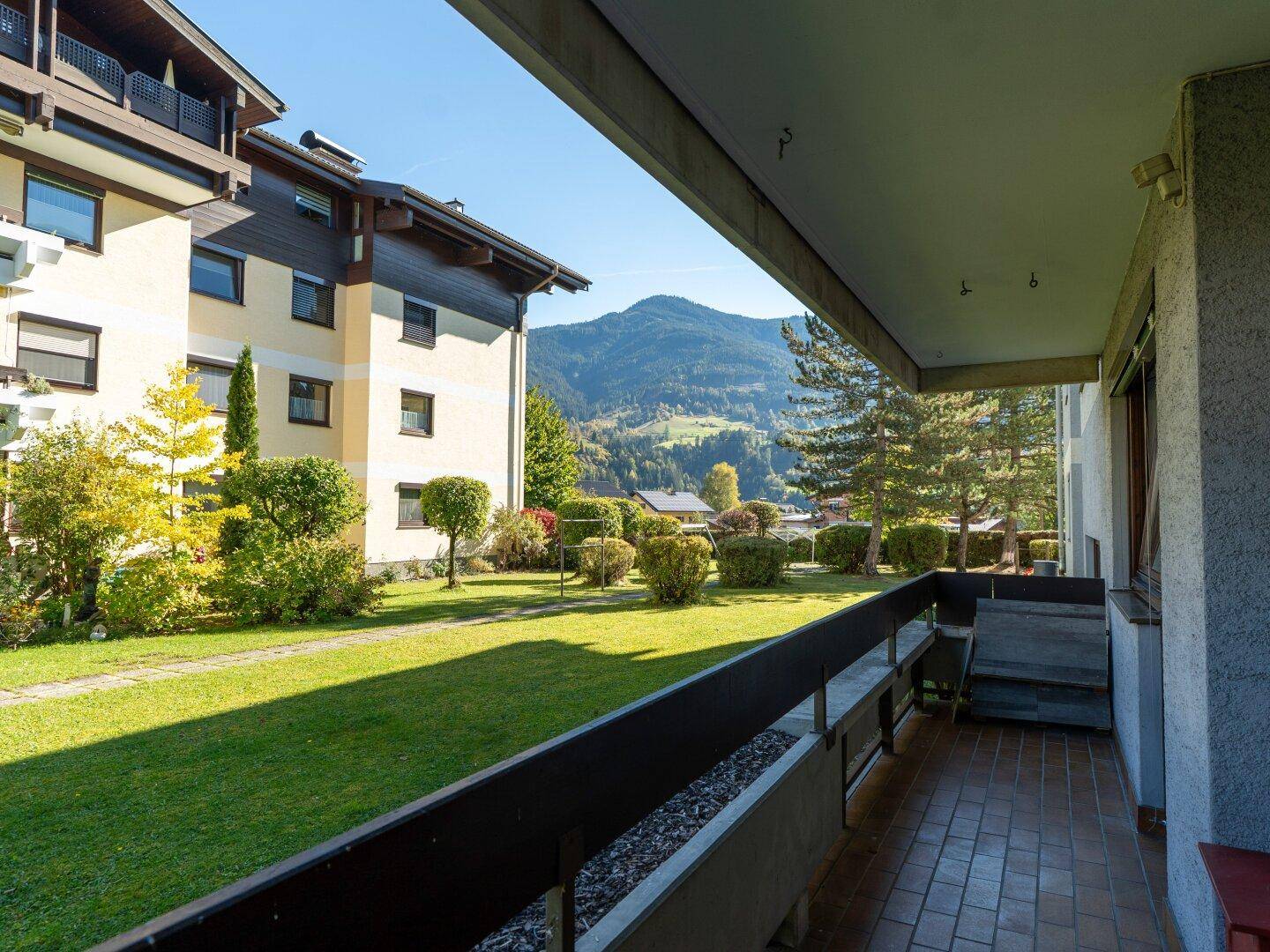 Balkon mit Blick auf den Gemeinschaftsgarten und die umliegende Berglandschaft.