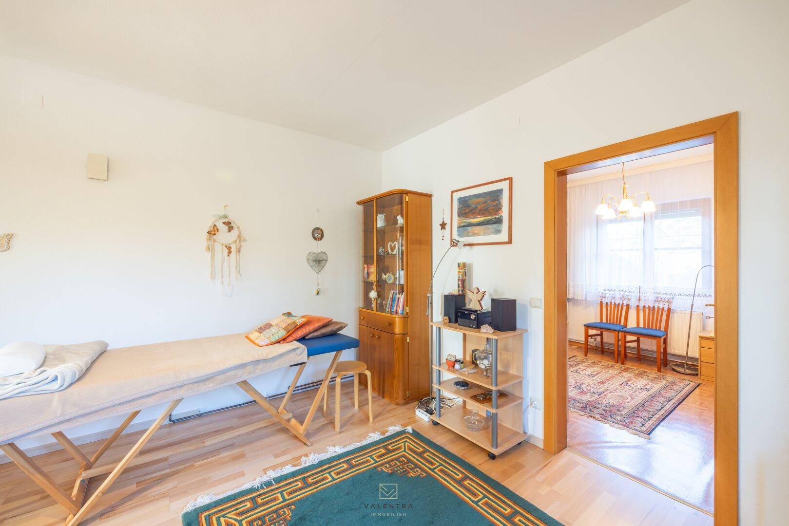 Wohnzimmer mit Holzboden, Vitrine und Durchgang zu einem weiteren Zimmer.