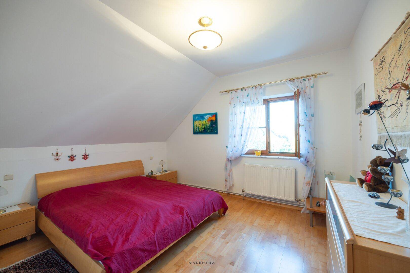 Helles Schlafzimmer im Dachgeschoss mit Doppelbett, Holzboden und Dachschräge.