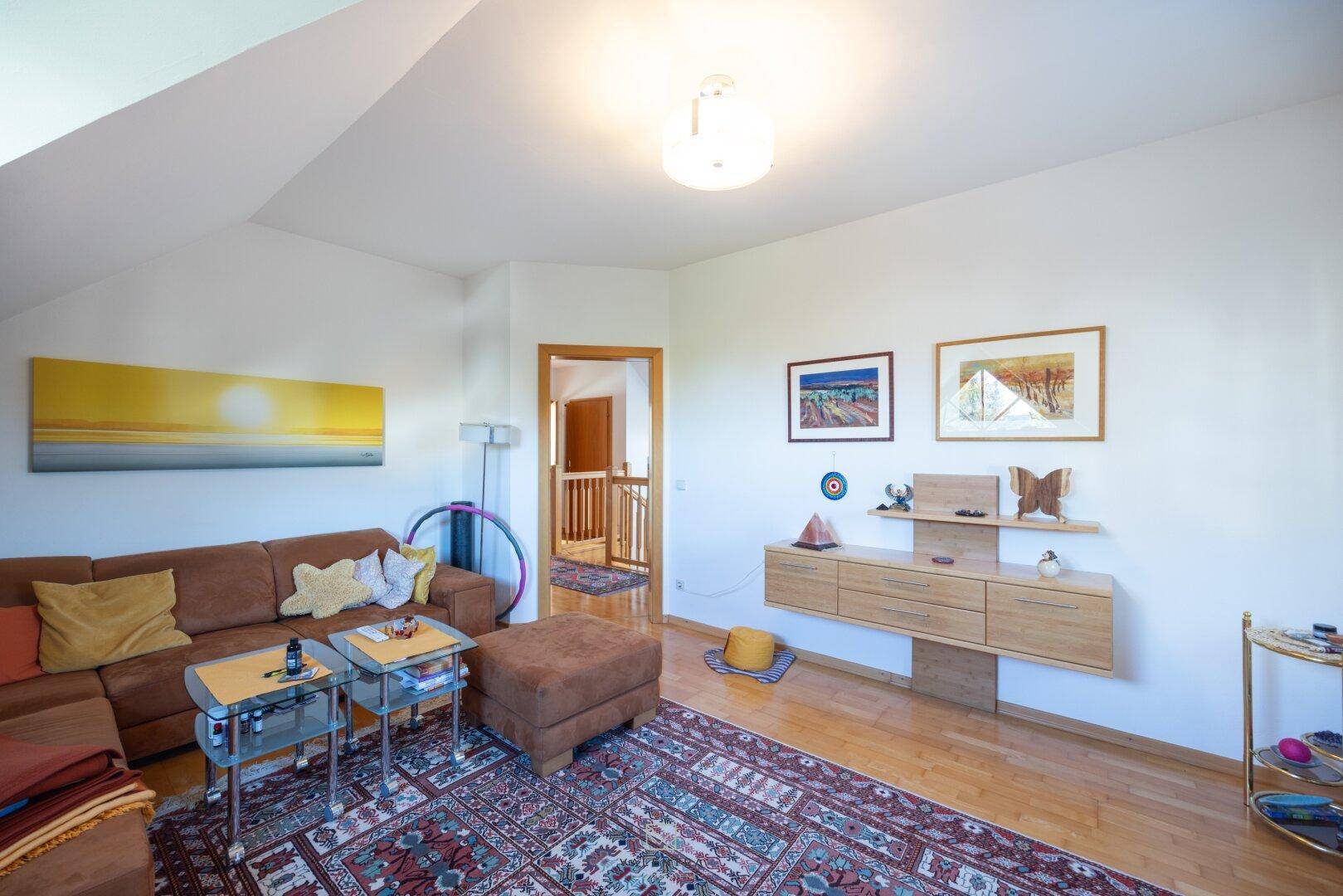 Geräumiges Wohnzimmer im Dachgeschoss mit Holzboden und moderner Dekoration.