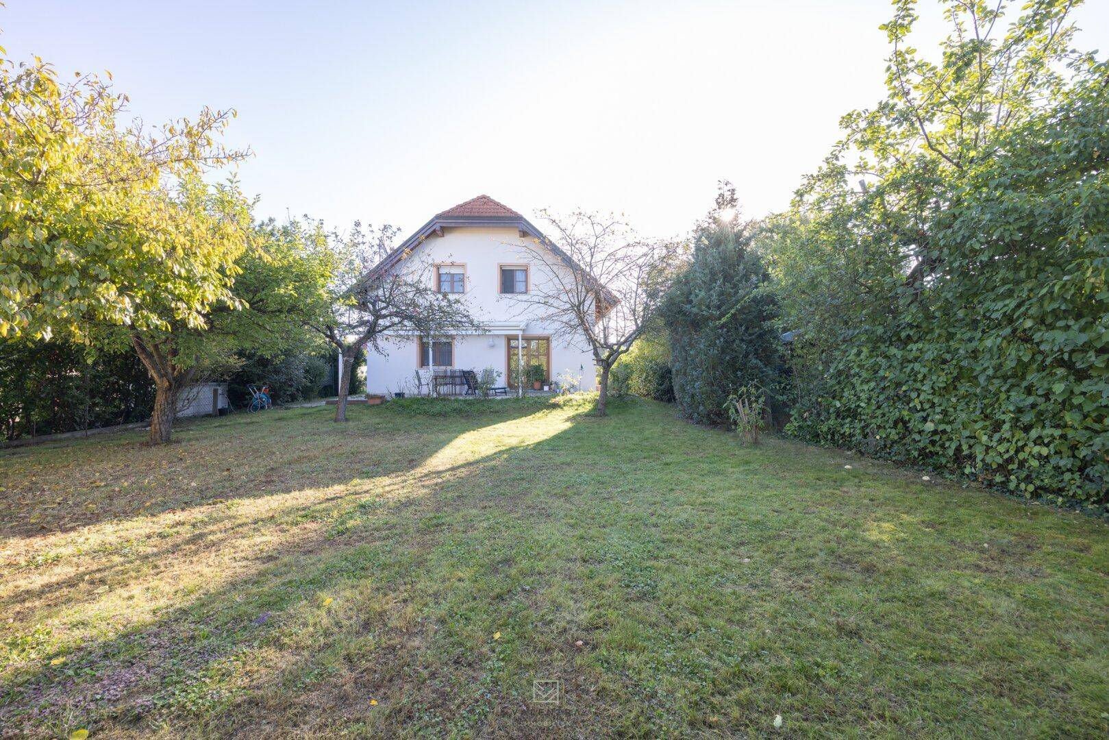 Weitläufiger Gartenbereich mit viel Grün und altem Baumbestand hinter dem Haus.