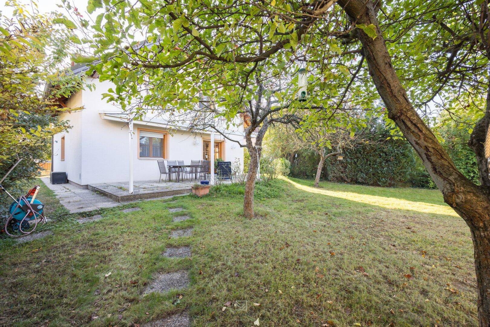 Terrasse mit Gartenmöbeln und Zugang zum weitläufigen Rasenbereich des Gartens.