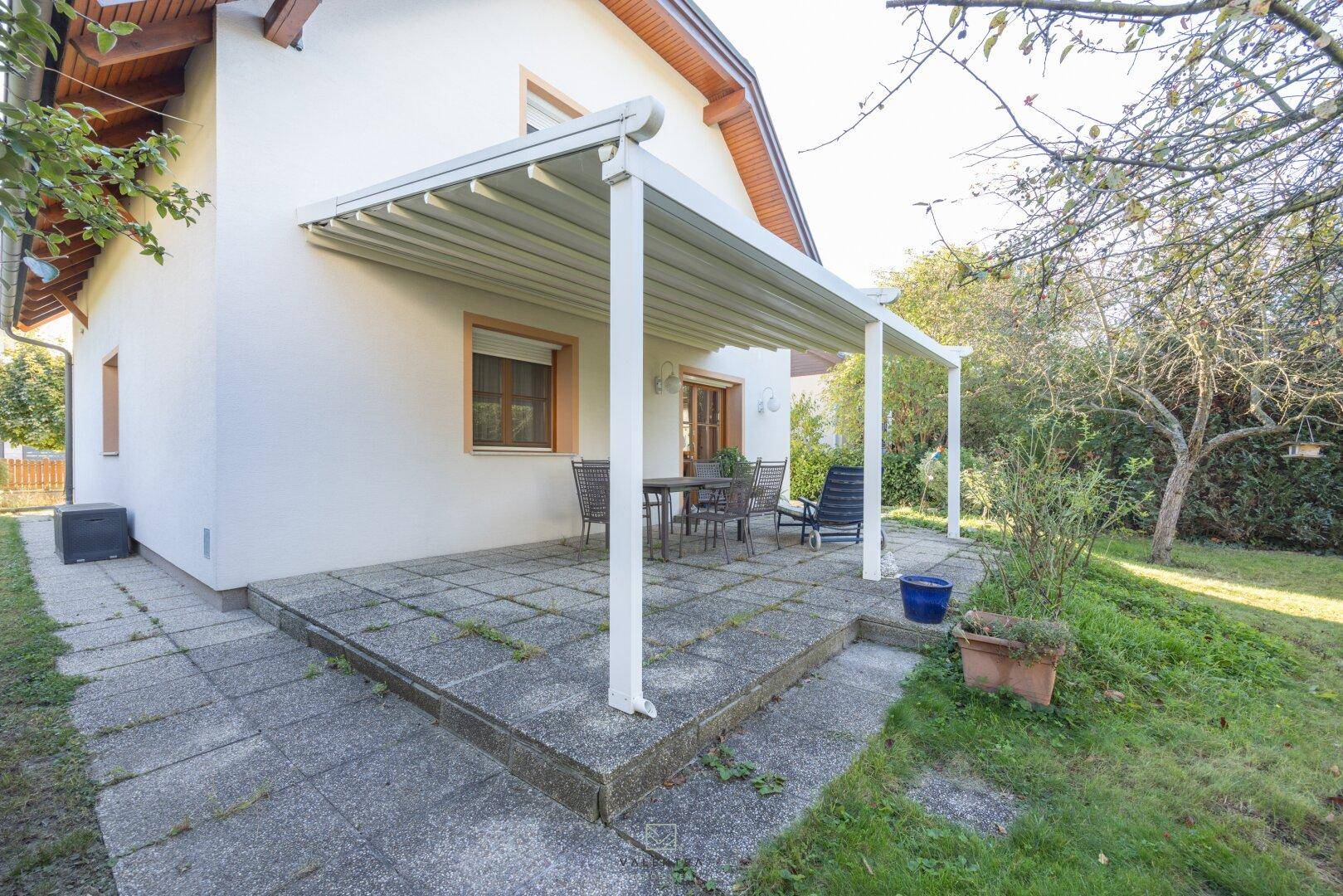 Geräumige Terrasse mit Überdachung und Blick auf den grünen Gartenbereich.