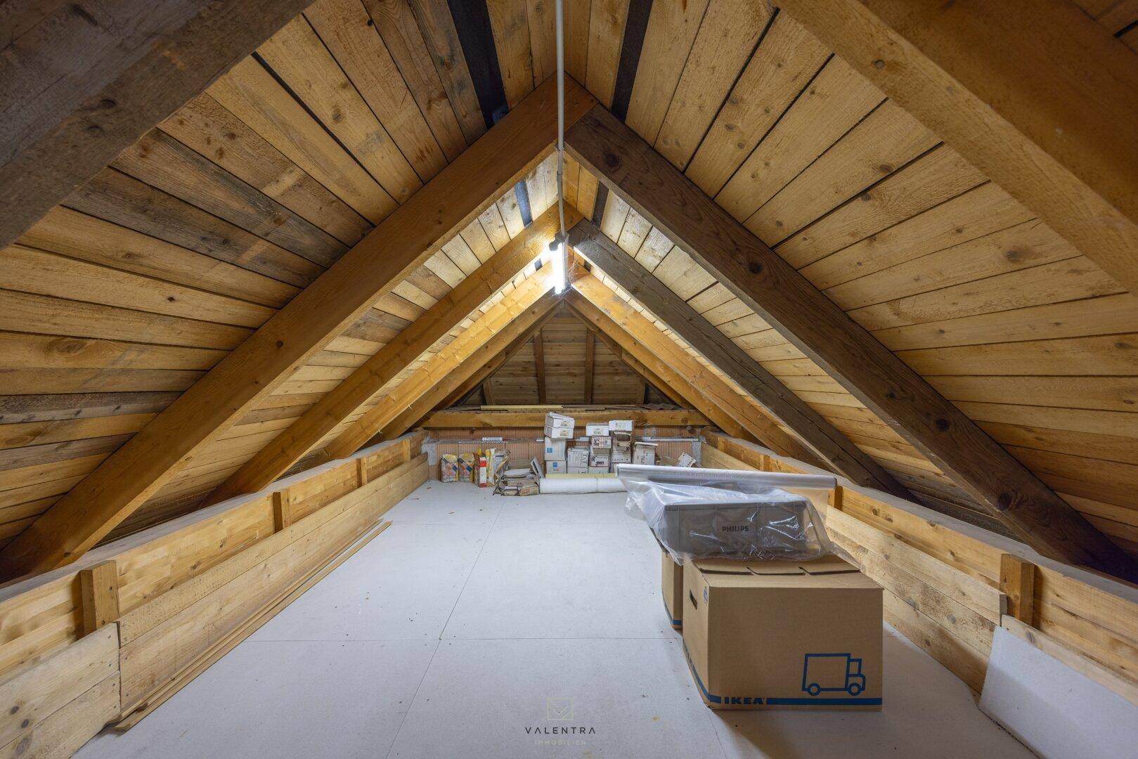 Geräumiger Dachboden mit sichtbaren Holzbalken und Lagerkartons, ideal als Stauraum.