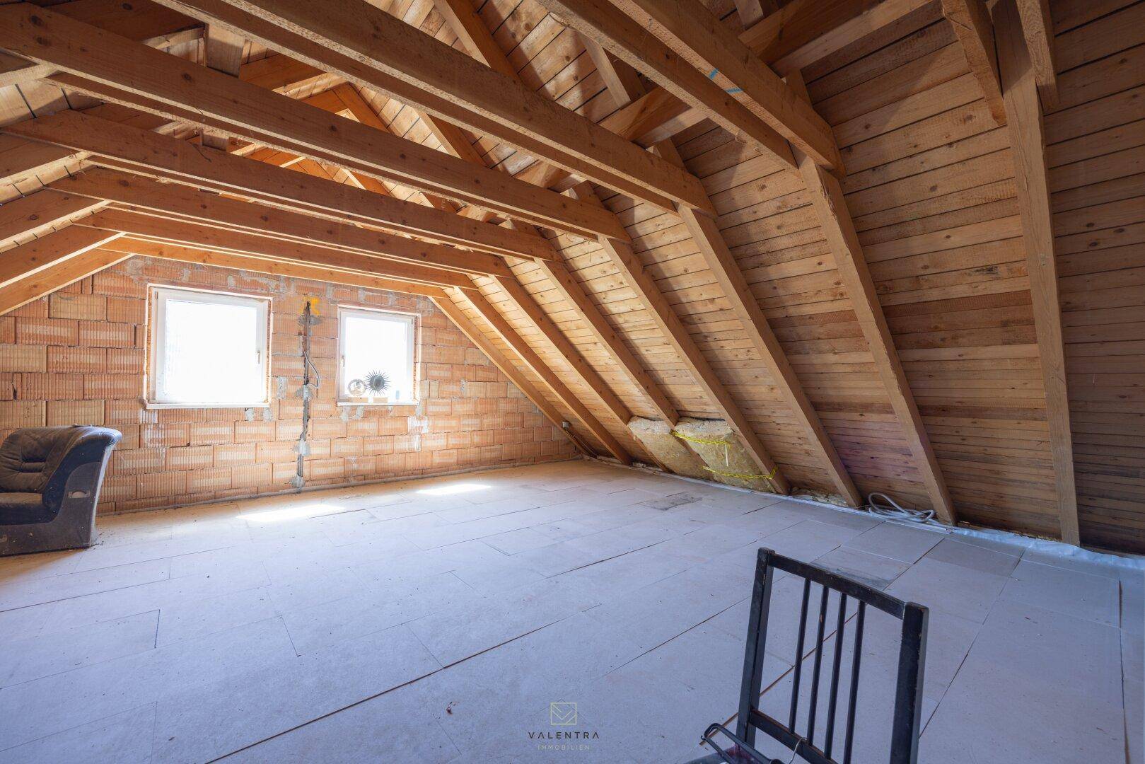 Großer Dachboden mit sichtbarer Holzkonstruktion und Fenstern, ideal für zukünftige Erweiterungen.