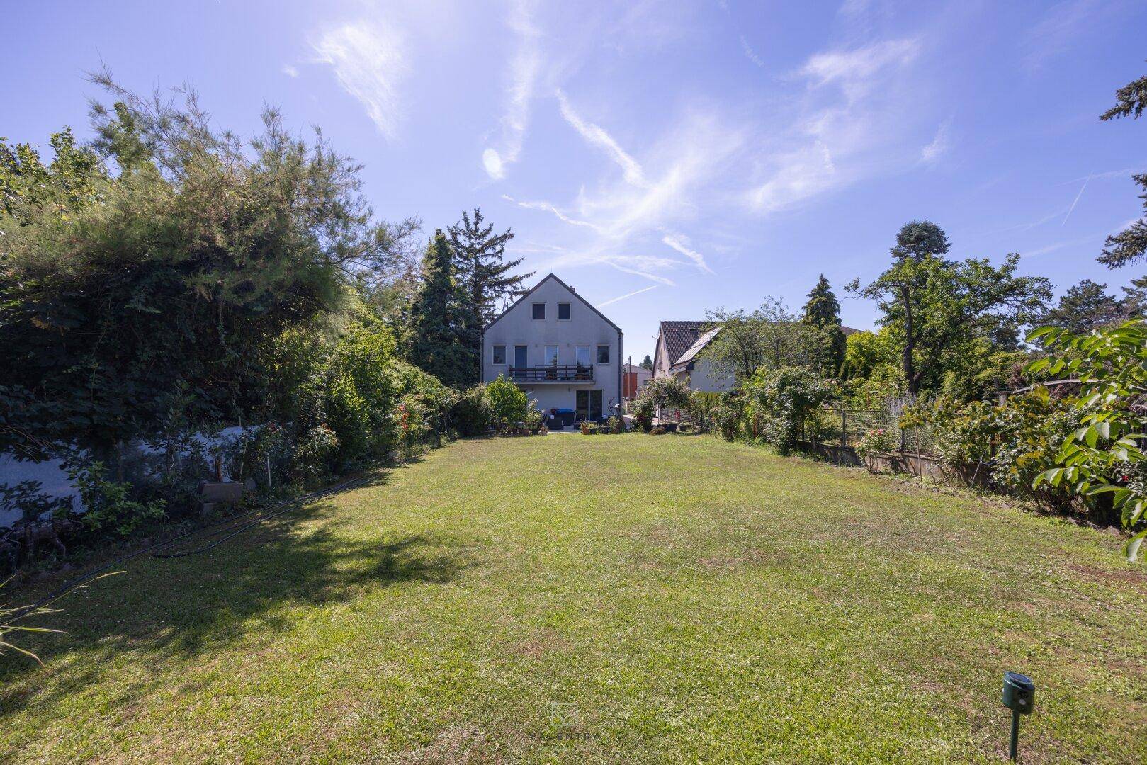 Großer, gepflegter Garten mit weitläufiger Rasenfläche und altem Baumbestand hinter dem Haus.