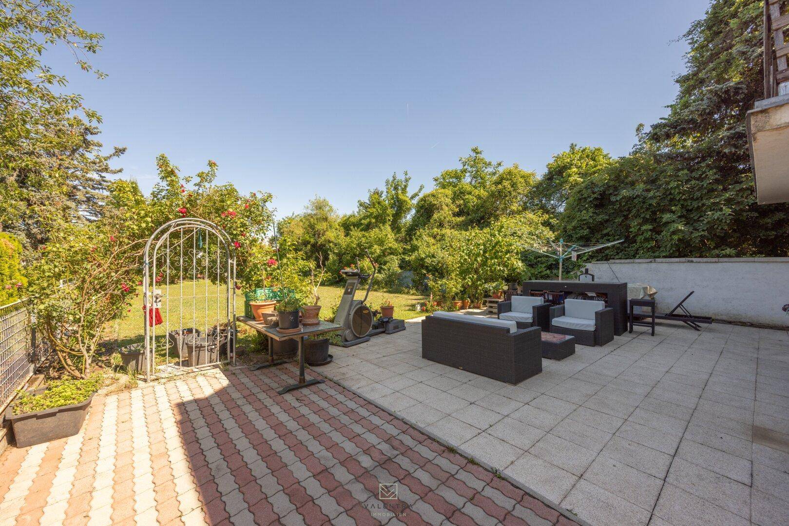 Große Terrasse mit Sitzgelegenheiten und Zugang zum weitläufigen Gartenbereich, ideal für Entspannung.
