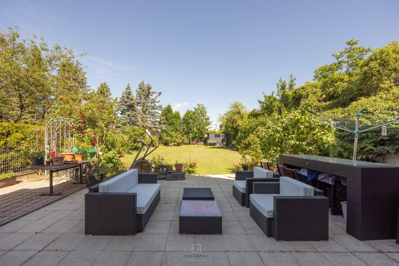 Weitläufige Terrasse mit bequemen Loungemöbeln und Blick auf den großen, grünen Garten.