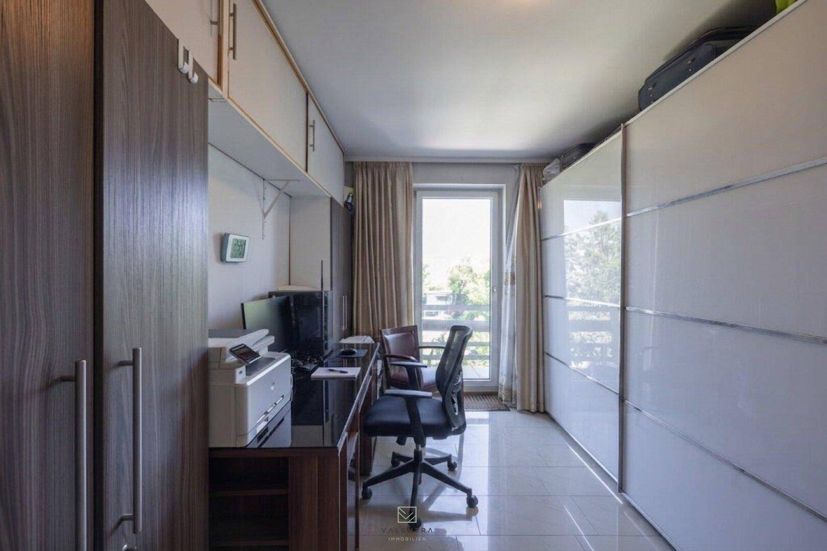 Funktionales Arbeitszimmer mit Schreibtisch, Bürostuhl, Computer und integrierten Kleiderschränken.