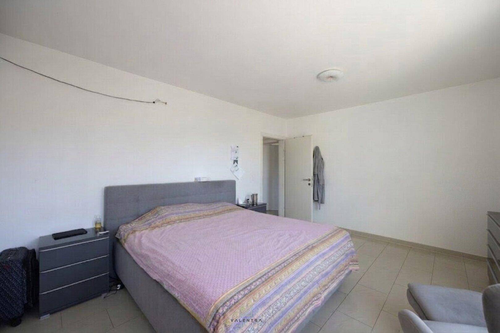 Geräumiges Schlafzimmer mit großem Bett, Nachttischen und Kommode, auf hellem Fliesenboden.