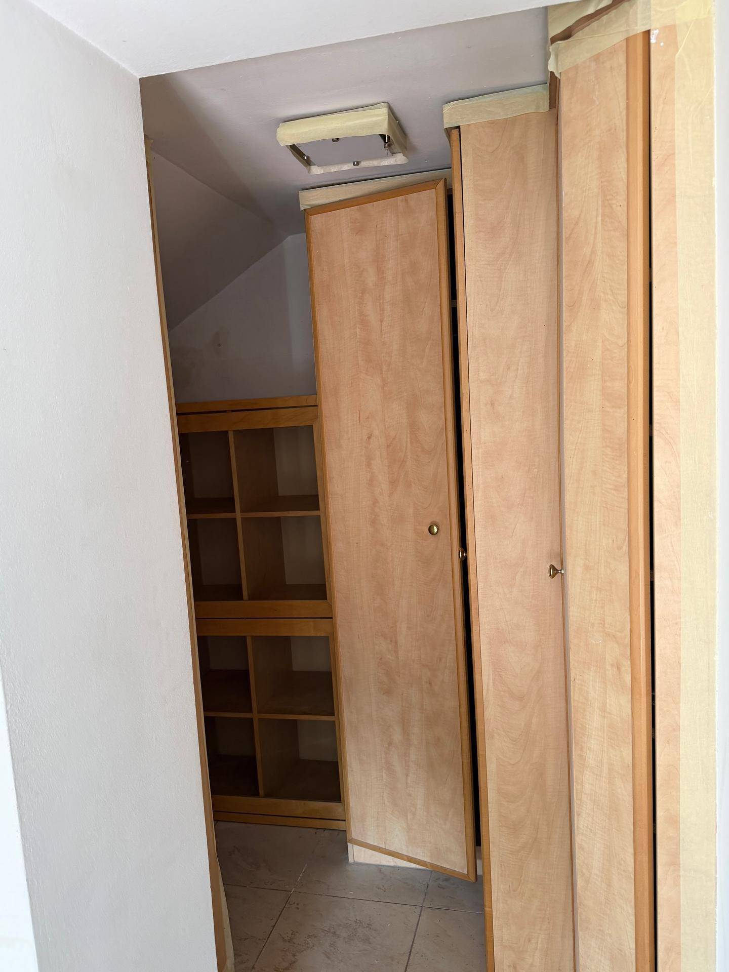 Abstellraum mit Holzschränken und Regalen unter einer Dachschräge, ideal für Lagerung.