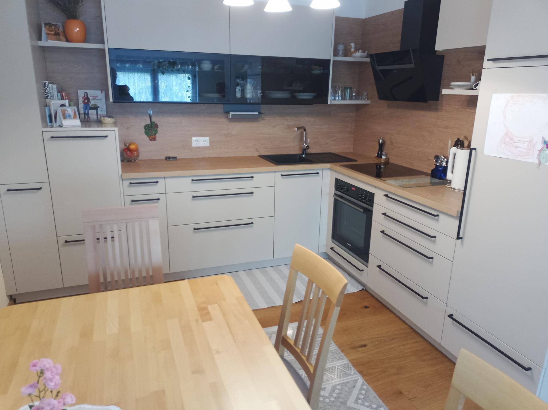 Moderne Einbauküche mit hellen Fronten, Holzarbeitsplatten und integriertem Essbereich.