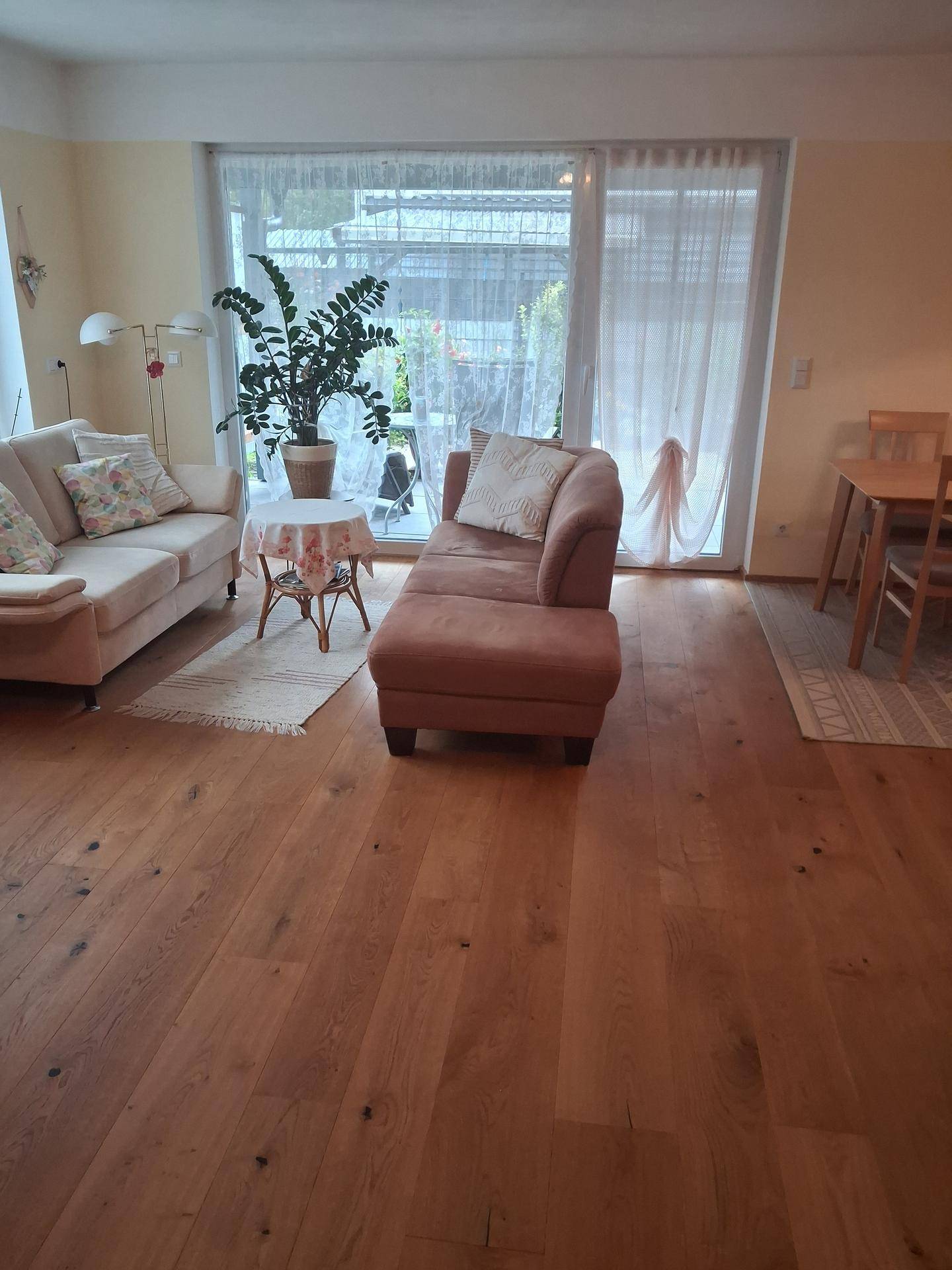 Gemütliches Wohnzimmer mit Holzboden, bequemen Möbeln und Zugang zum Außenbereich.