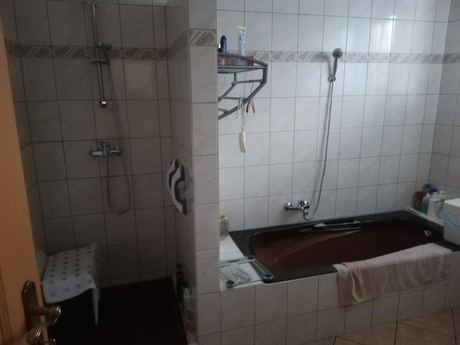 Badezimmer mit beigefarbenen Fliesen, integrierter Badewanne und separater Dusche.