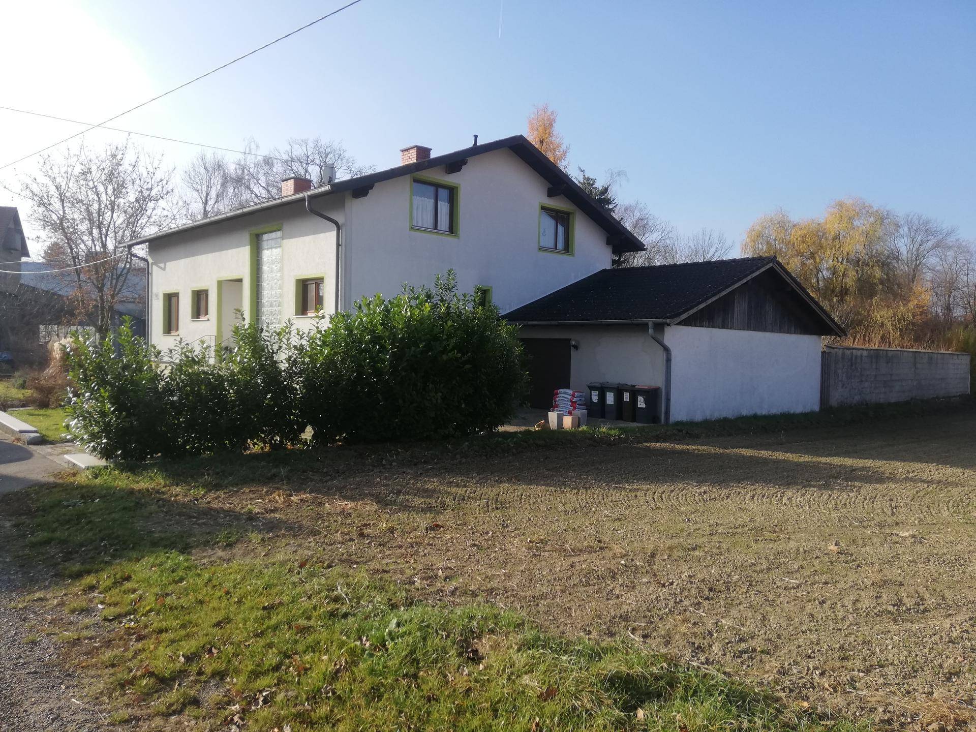 Seitenansicht des Einfamilienhauses mit angrenzender Garage und großem Grundstück.