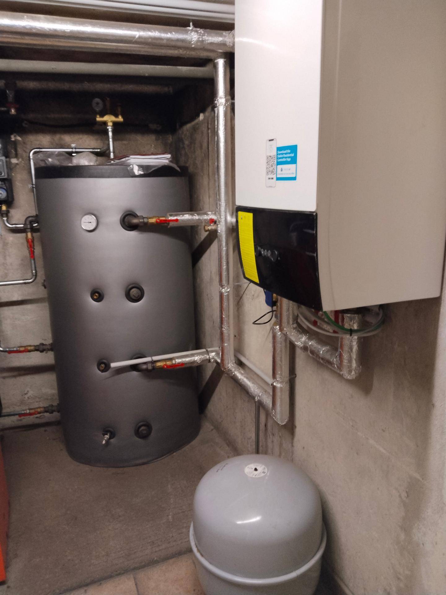 Heizungsraum mit modernem Heizkessel und Warmwasserspeicher in einem funktionalen Kellerbereich.