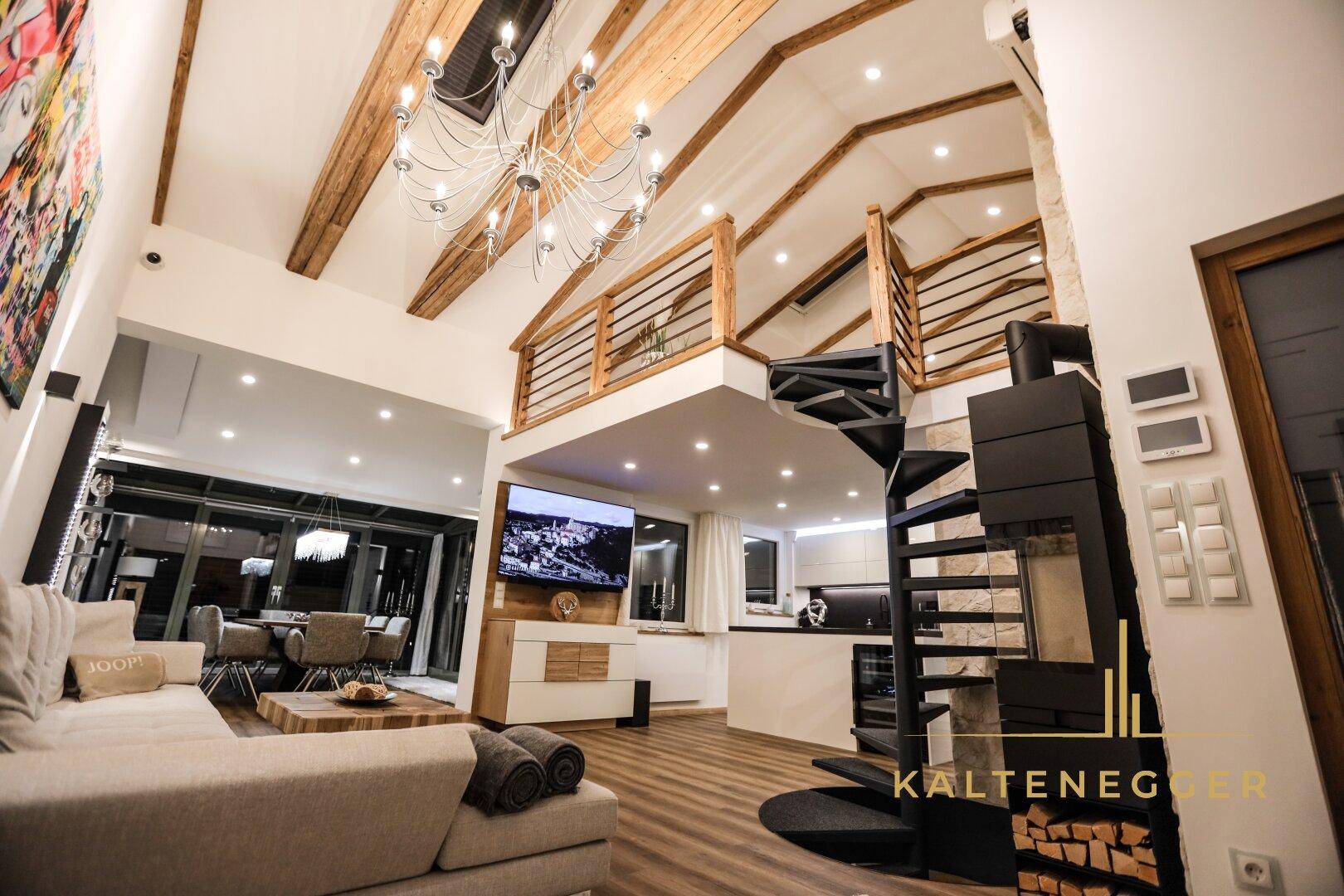 Geräumiger Wohn- und Essbereich mit hohen Decken, Holzbalken und Wendeltreppe.