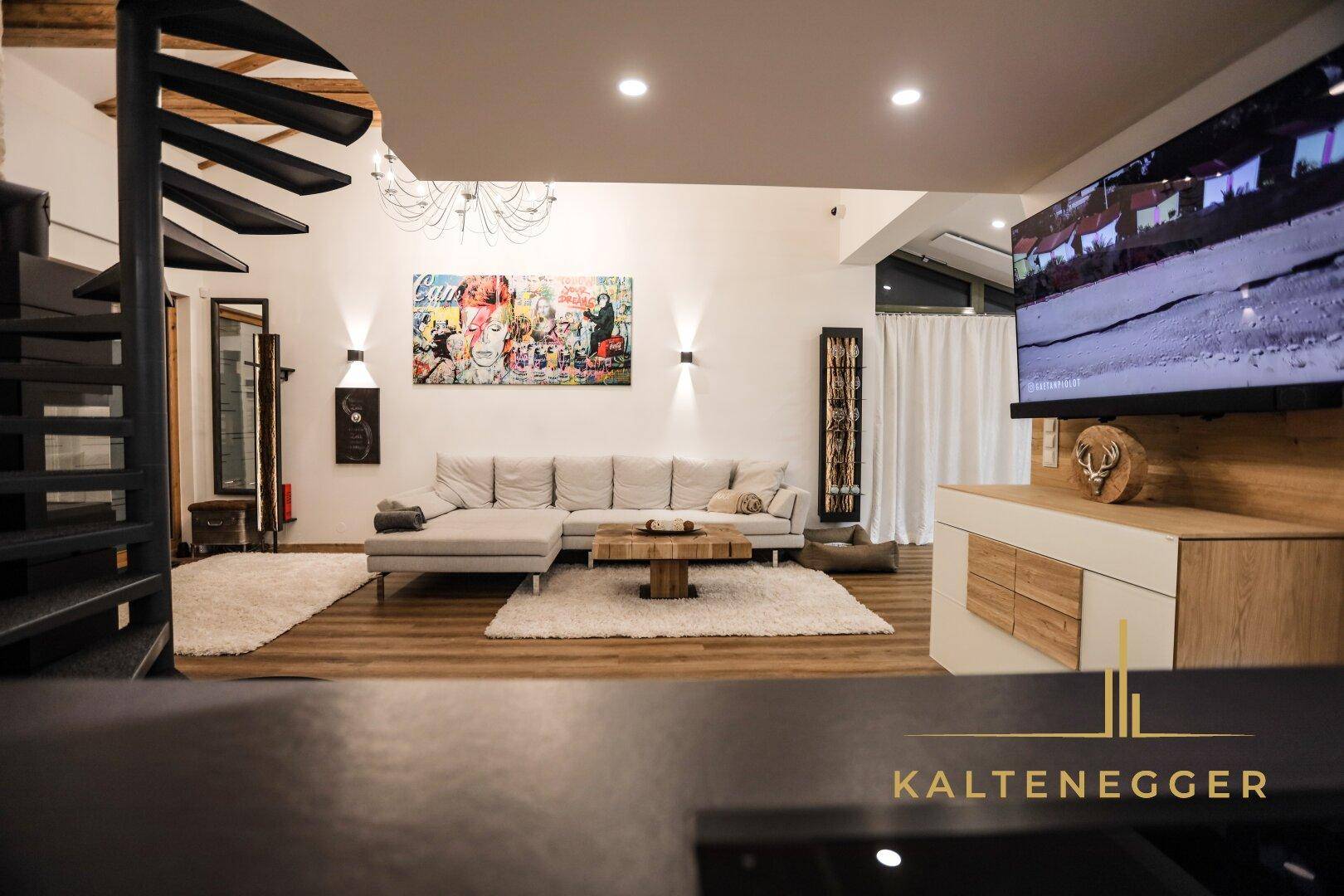 Heller Wohnbereich mit beigem Ecksofa, Holzboden und moderner Kunst an der Wand.