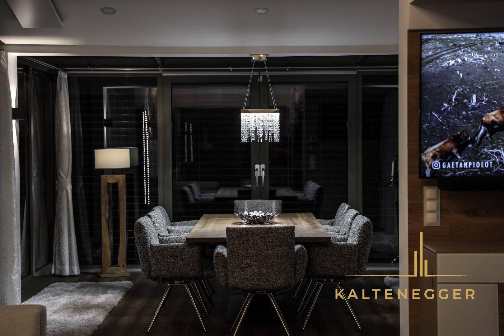 Abendliche Atmosphäre im Essbereich mit elegantem Holztisch und Designerleuchte.