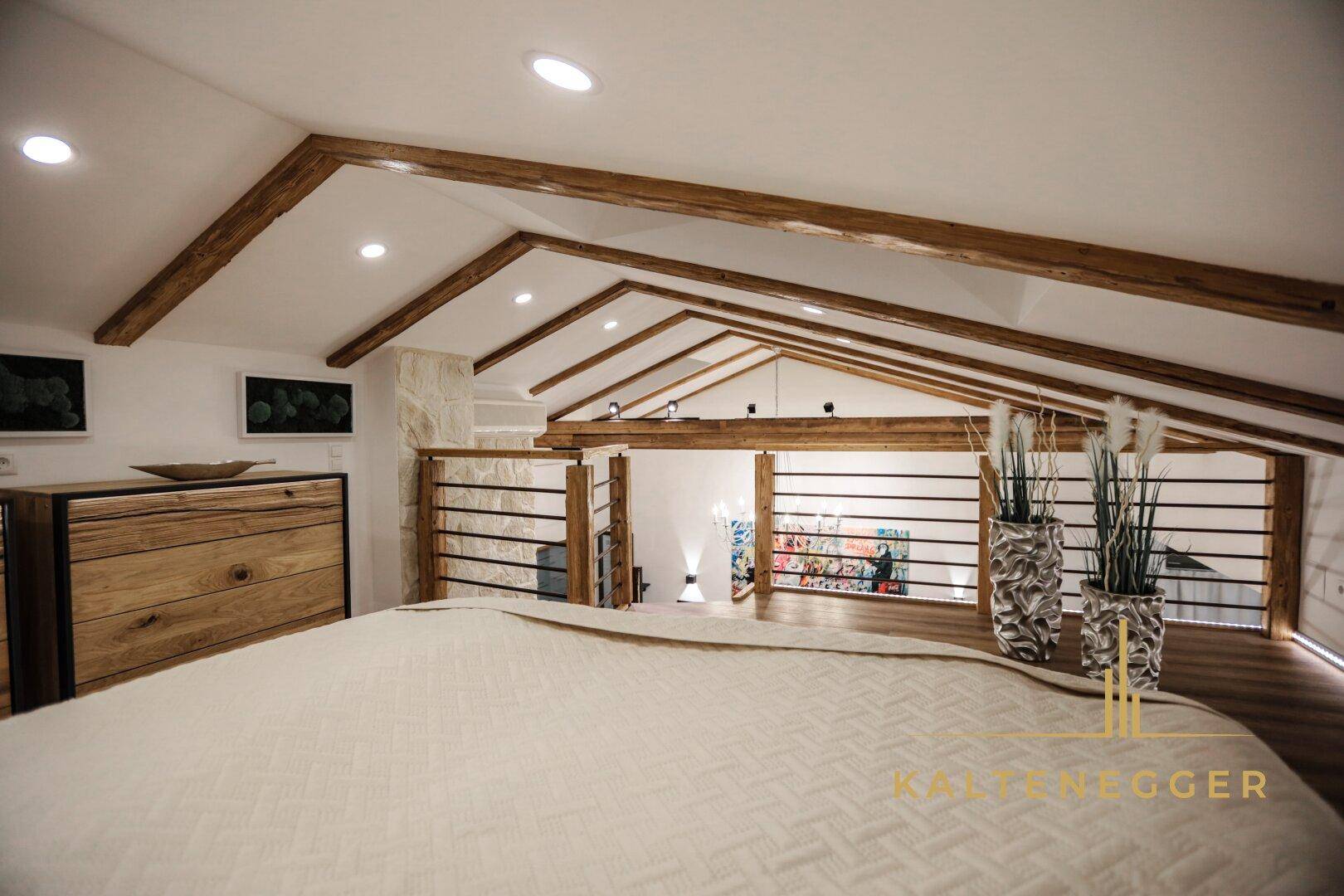 Gemütlicher Schlafbereich im Dachgeschoss mit Holzbalken und schrägen Decken.