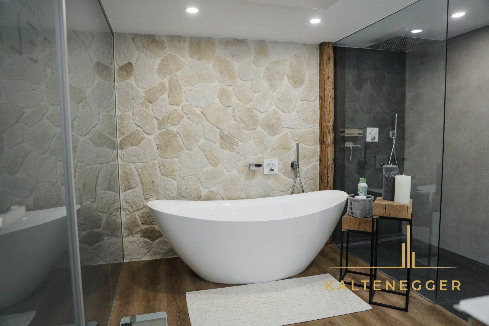 Modernes Badezimmer mit freistehender Badewanne und Steinwandakzent.
