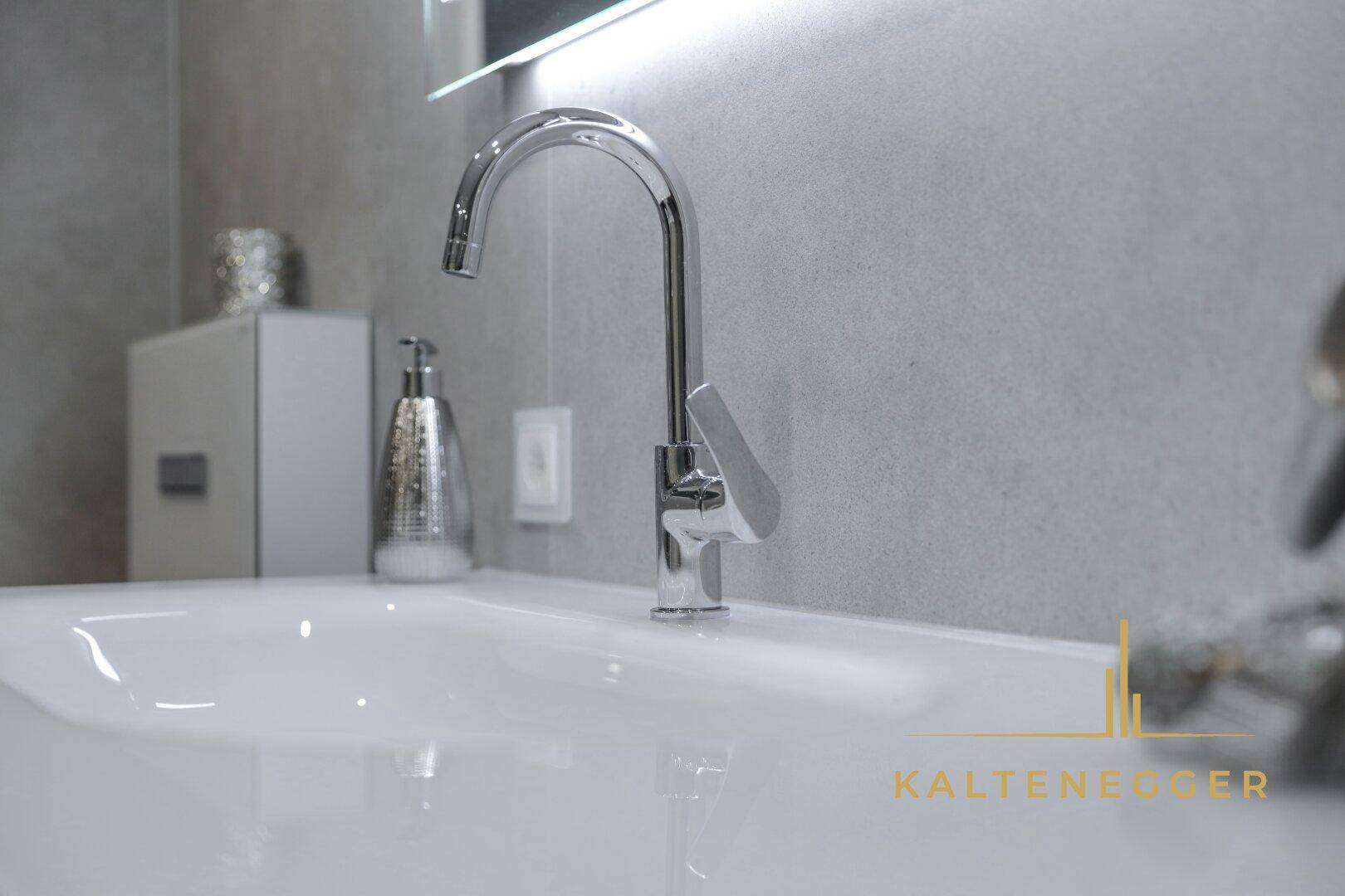 Detailaufnahme eines modernen Waschbeckens mit elegantem Wasserhahn im Badezimmer.