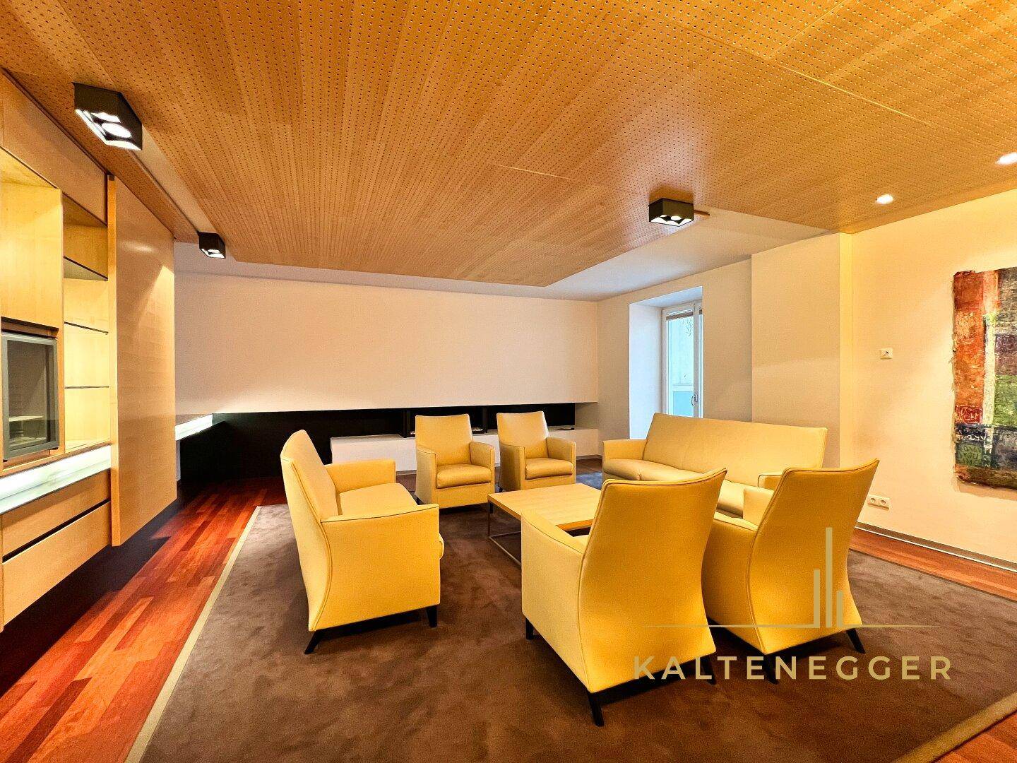Gemütlicher Loungebereich mit gelben Sesseln, Holzboden und perforierter Holzdecke, ideal zum Entspannen.