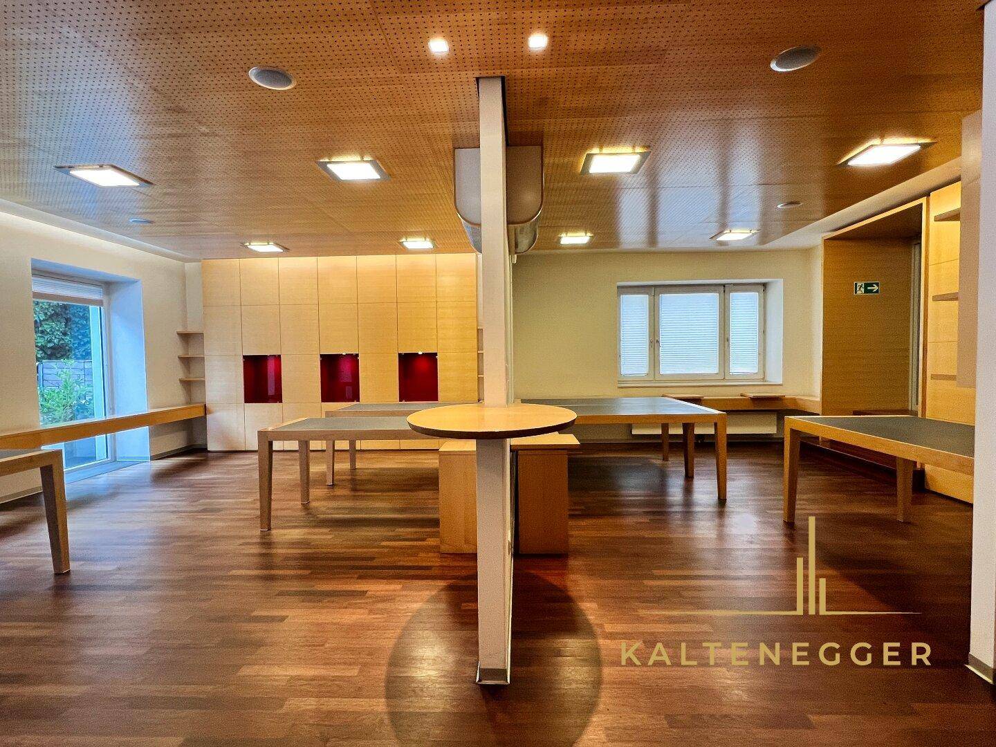 Geräumiger Arbeitsbereich mit Holzboden, perforierter Holzdecke und integrierten Schränken für optimale Organisation.