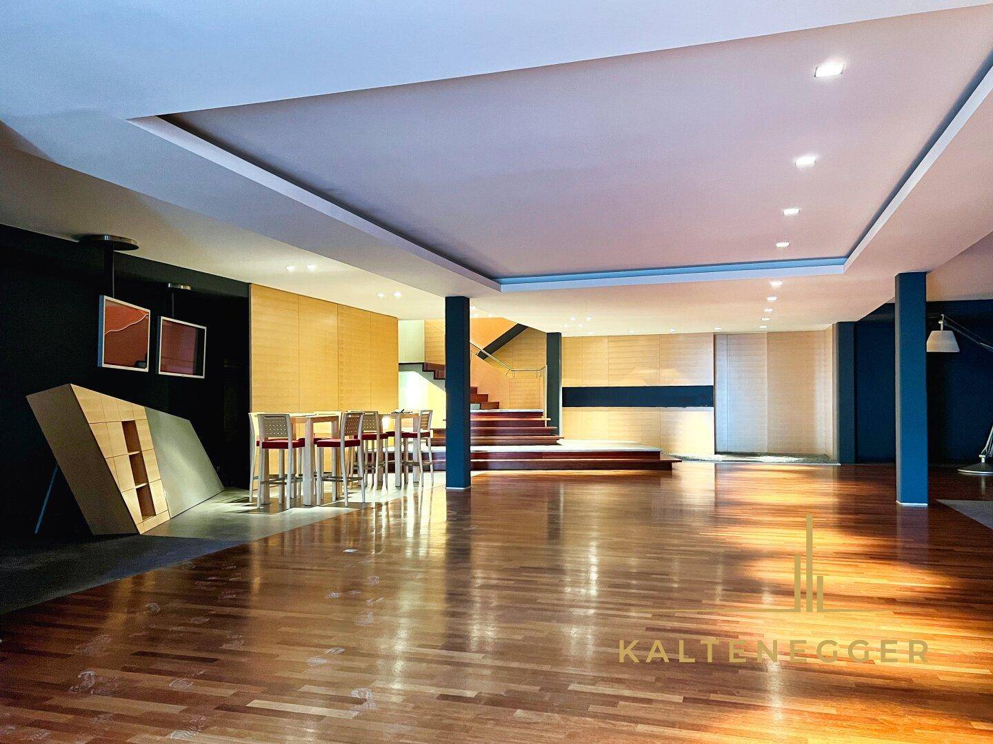 Weitläufiger, offener Gewerberaum mit glänzendem Holzfußboden, einer Treppe und moderner Einrichtung.