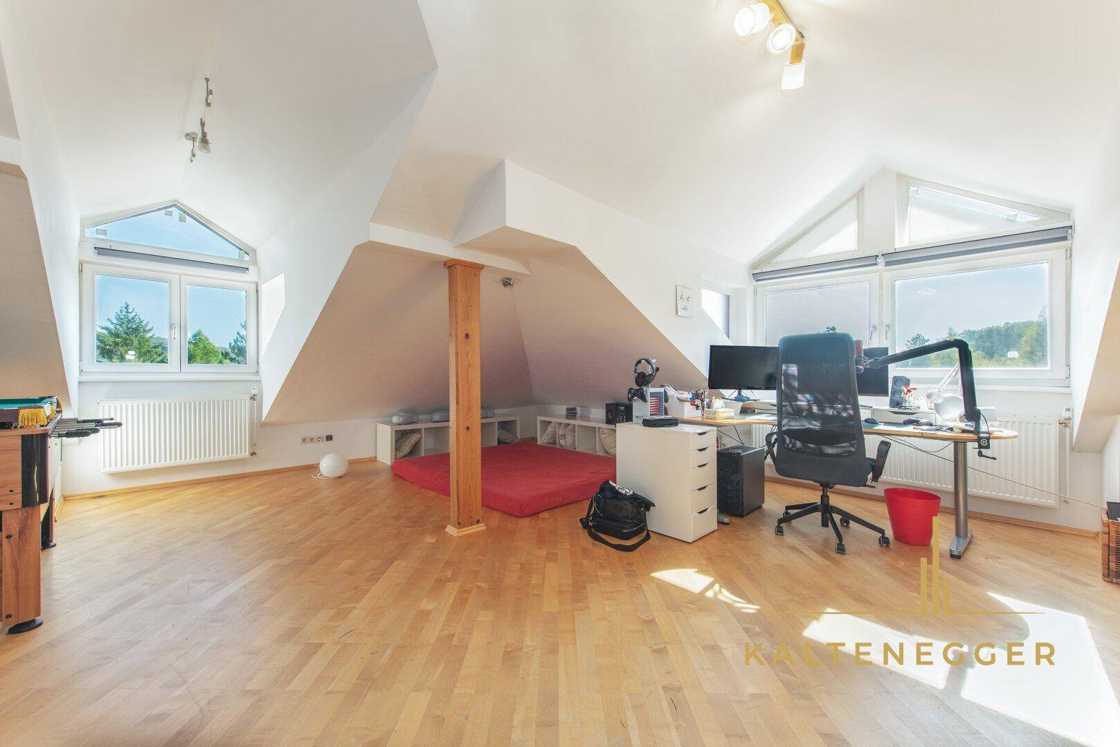 Helles Dachgeschosszimmer mit Holzboden, Schrägen und großen Fenstern, ideal als Büro oder Hobbyraum.
